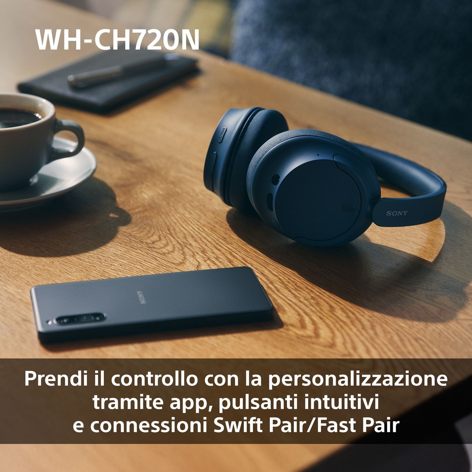 Cuffie e smartphone su un tavolo di legno. Presenti una tazza di caffè e un taccuino.