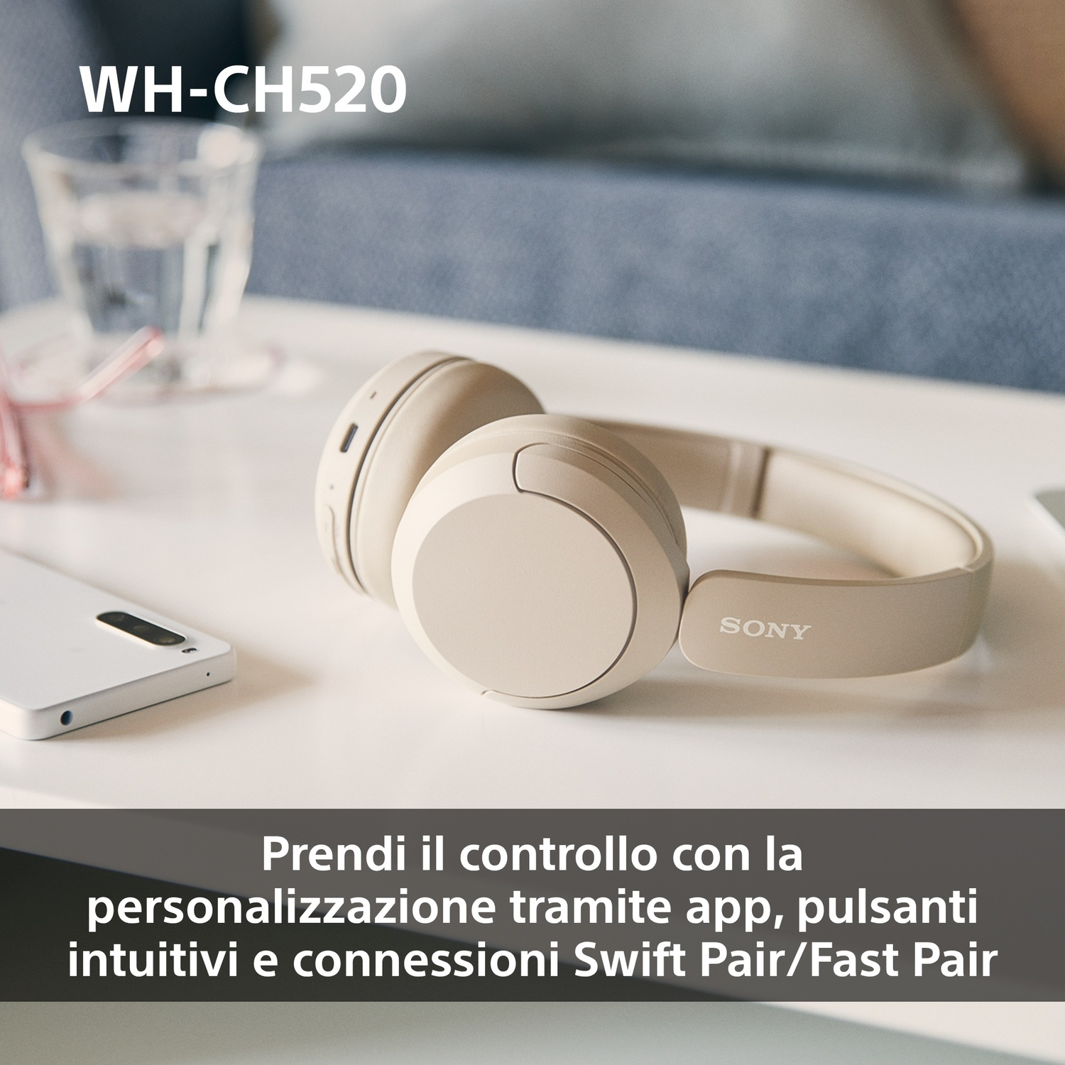 Cuffie su un tavolo bianco, con un telefono e un bicchiere. Il prodotto è WH-CH520.