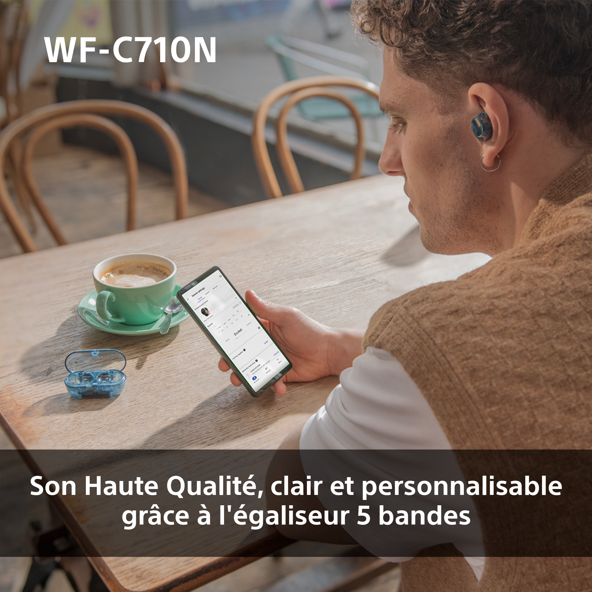 Ein Mann benutzt ein Telefon mit Ohrhörern und eine Kaffeetasse auf einem Holztisch.