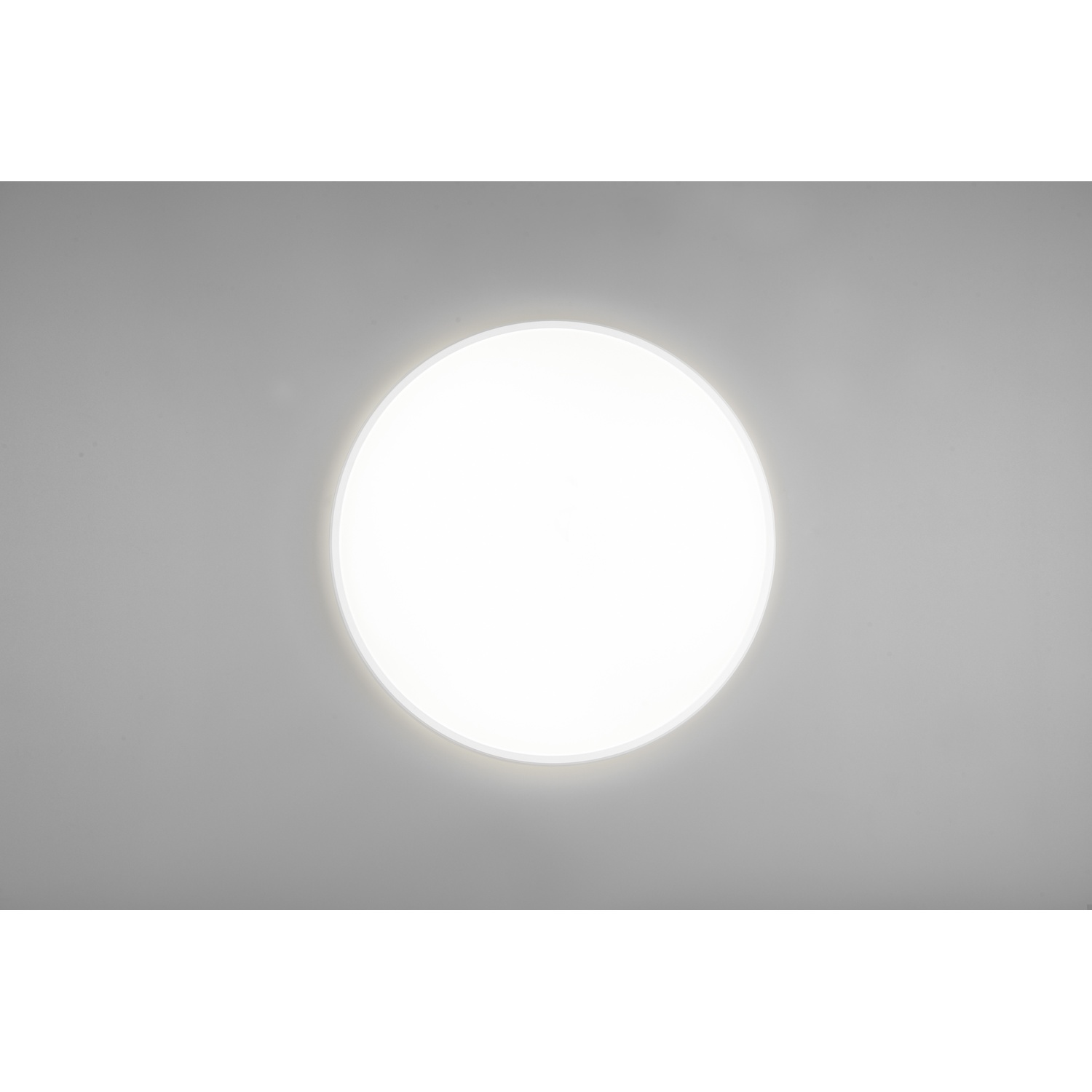 Una luce da soffitto bianca brillante su sfondo grigio. La luce è rotonda.