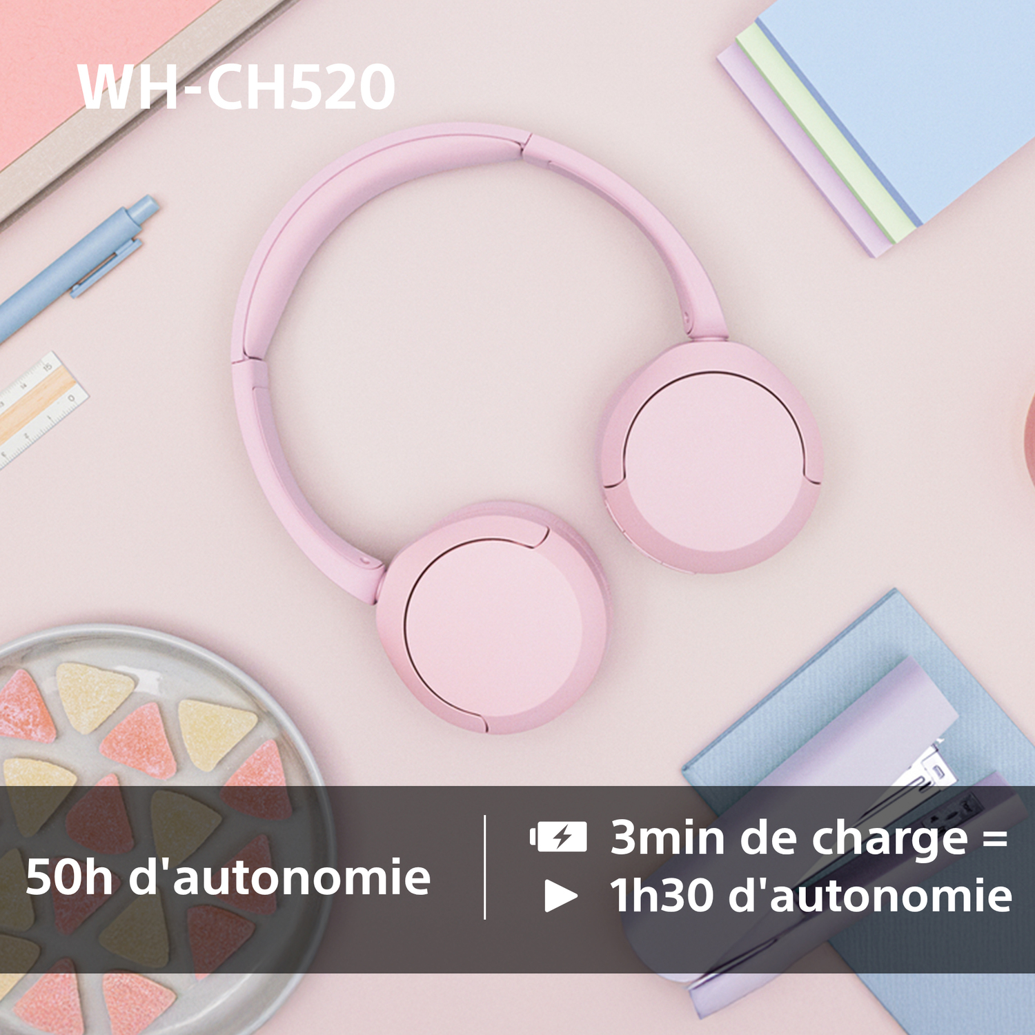 Un casque sans fil rose sur un bureau avec des articles de papeterie et des bonbons, avec du texte sur l'autonomie.