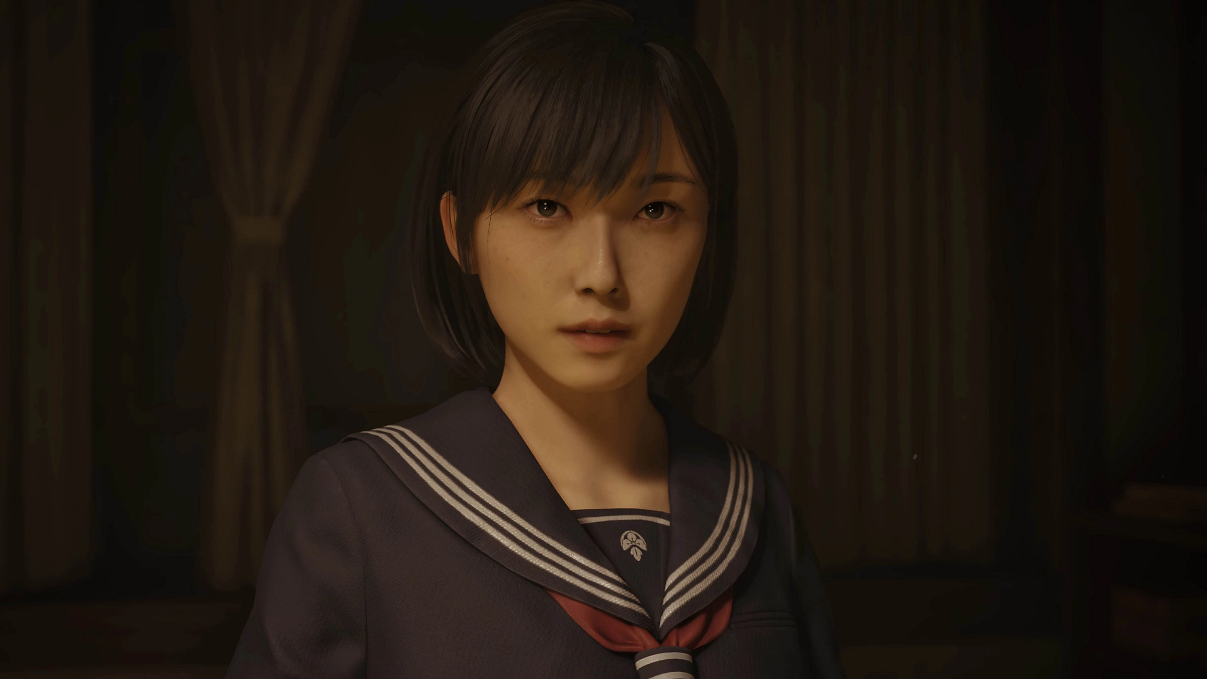 Eine junge asiatische Frau, die in einer schwach beleuchteten Umgebung in die Kamera blickt. Sie trägt eine dunkelblaue Uniform.