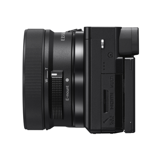 Widok z boku czarnego aparatu z obiektywem, elementami sterującymi i bocznymi drzwiami do wejść.