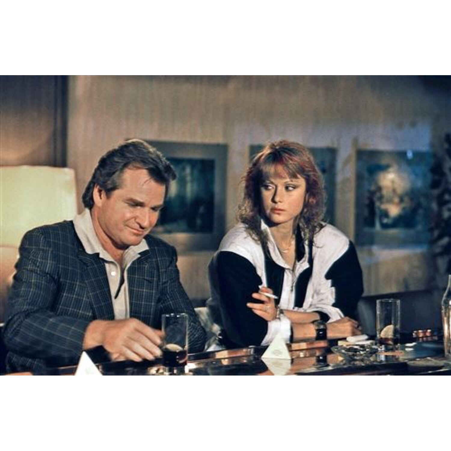 Two people at a table. A man with a plaid jacket and a woman with a black and white top are sitting down.