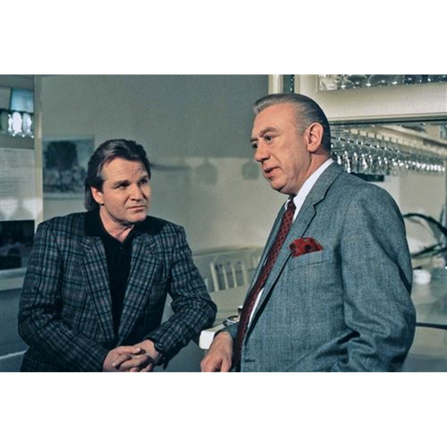 Two men in a bar. One wears a plaid jacket and the other a gray suit. 