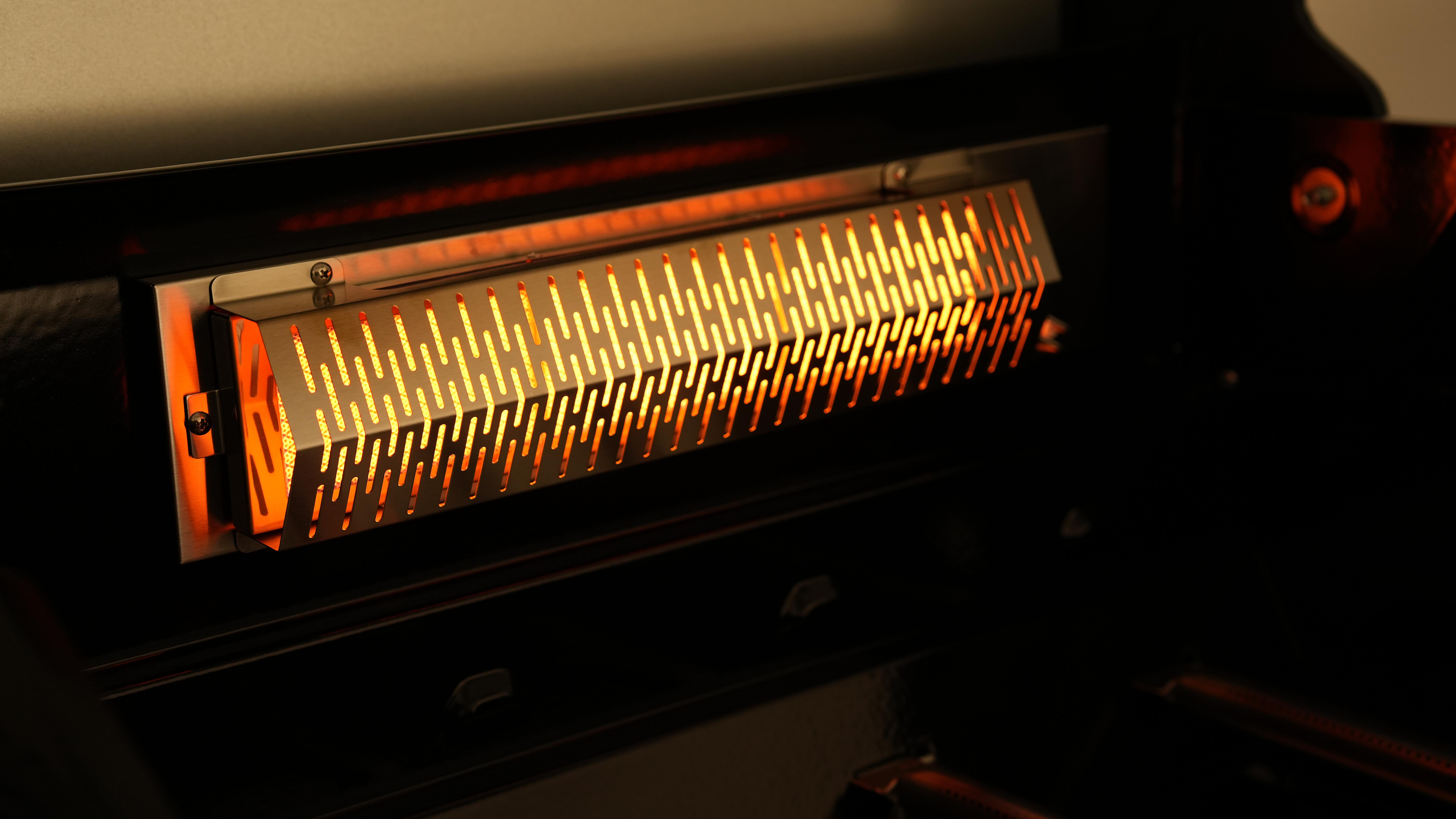 Der glühende Innenraum eines Grills. Das Heizelement ist sichtbar, mit einer Metallabdeckung.