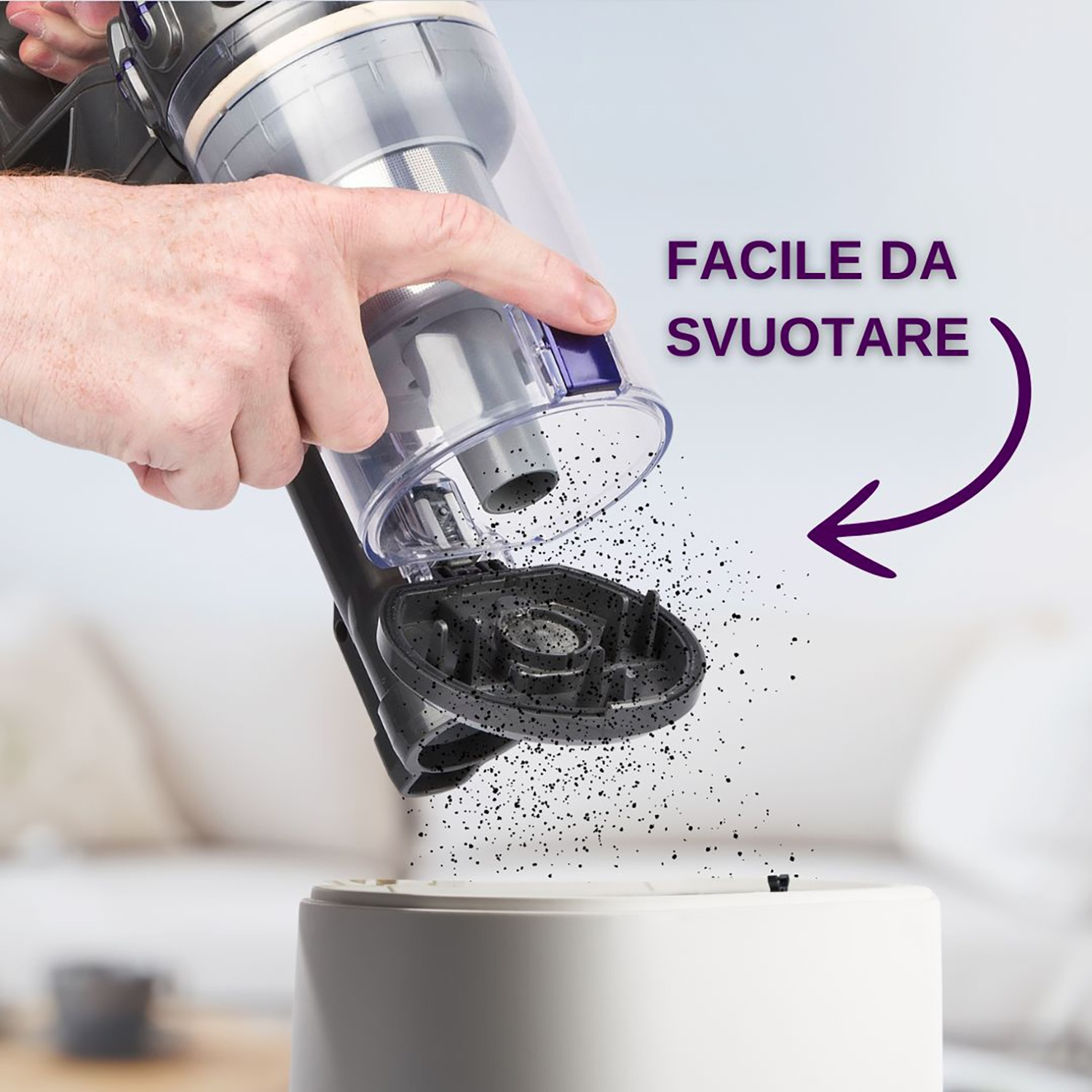 Persona che svuota un aspirapolvere. Lo sporco viene rilasciato in un contenitore. Il testo dice: facile da svuotare.
