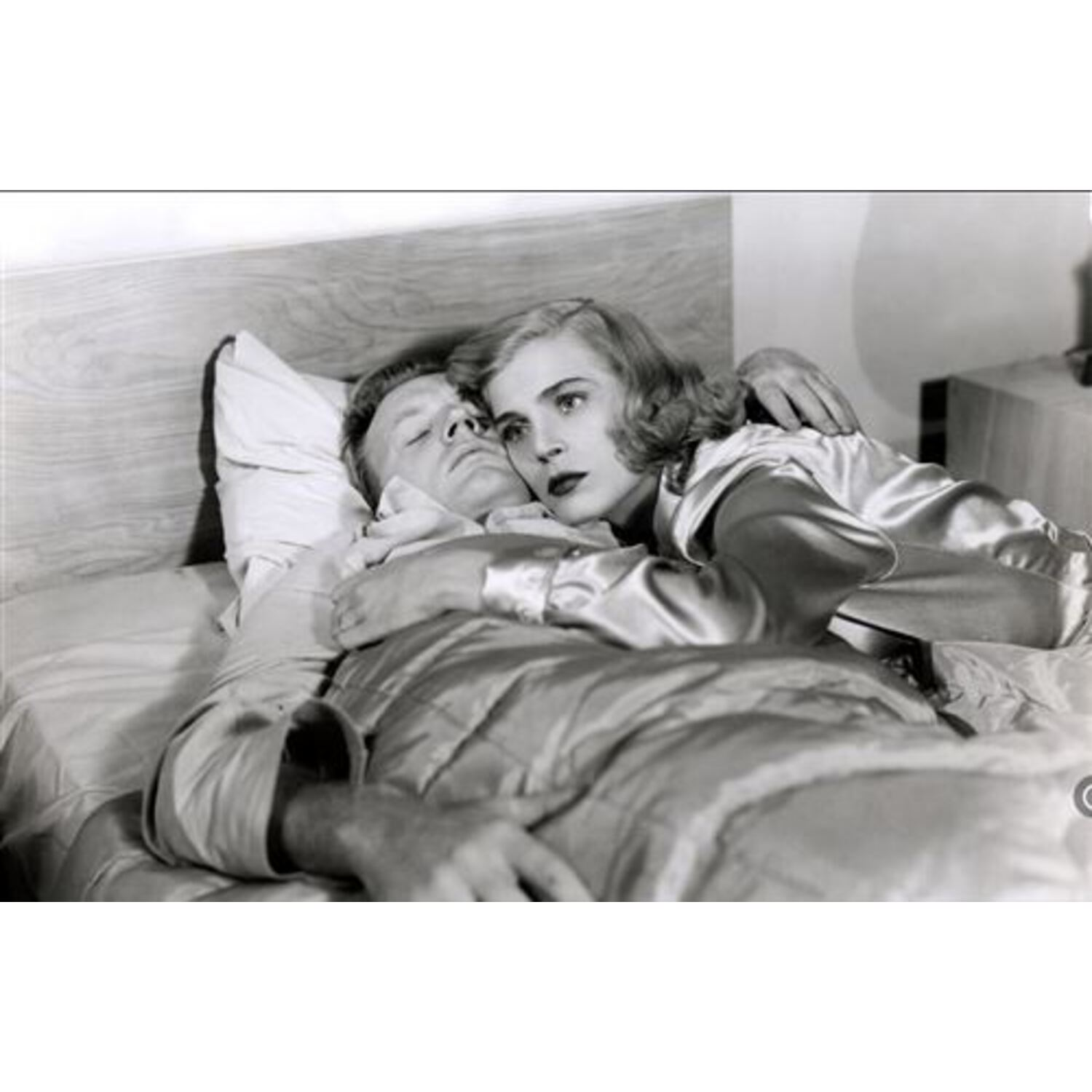 Een zwart-wit foto van een man en een vrouw die elkaar omhelzen op een bed.