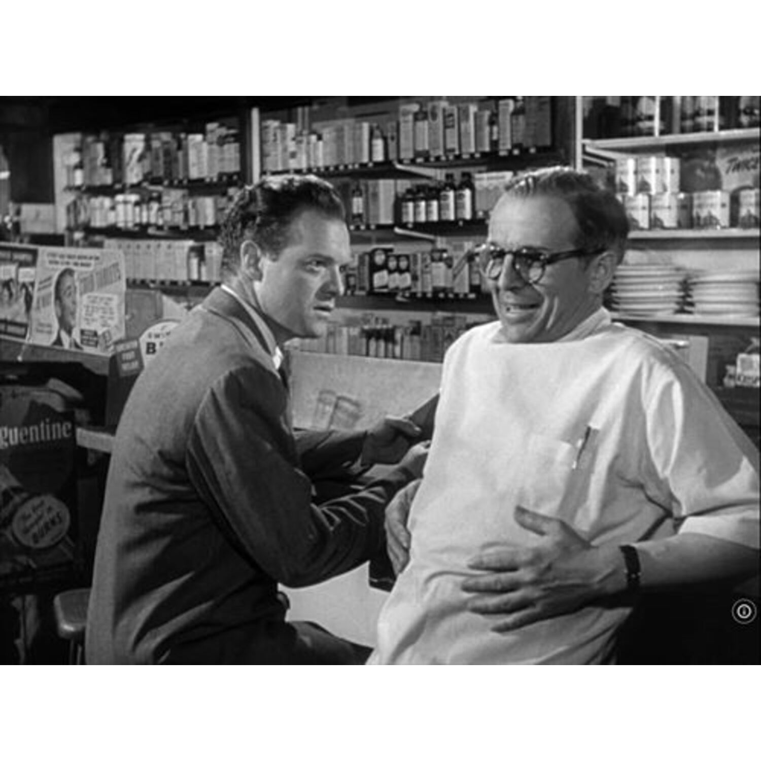 Deux hommes dans un restaurant, l'un sourit et l'autre parle.