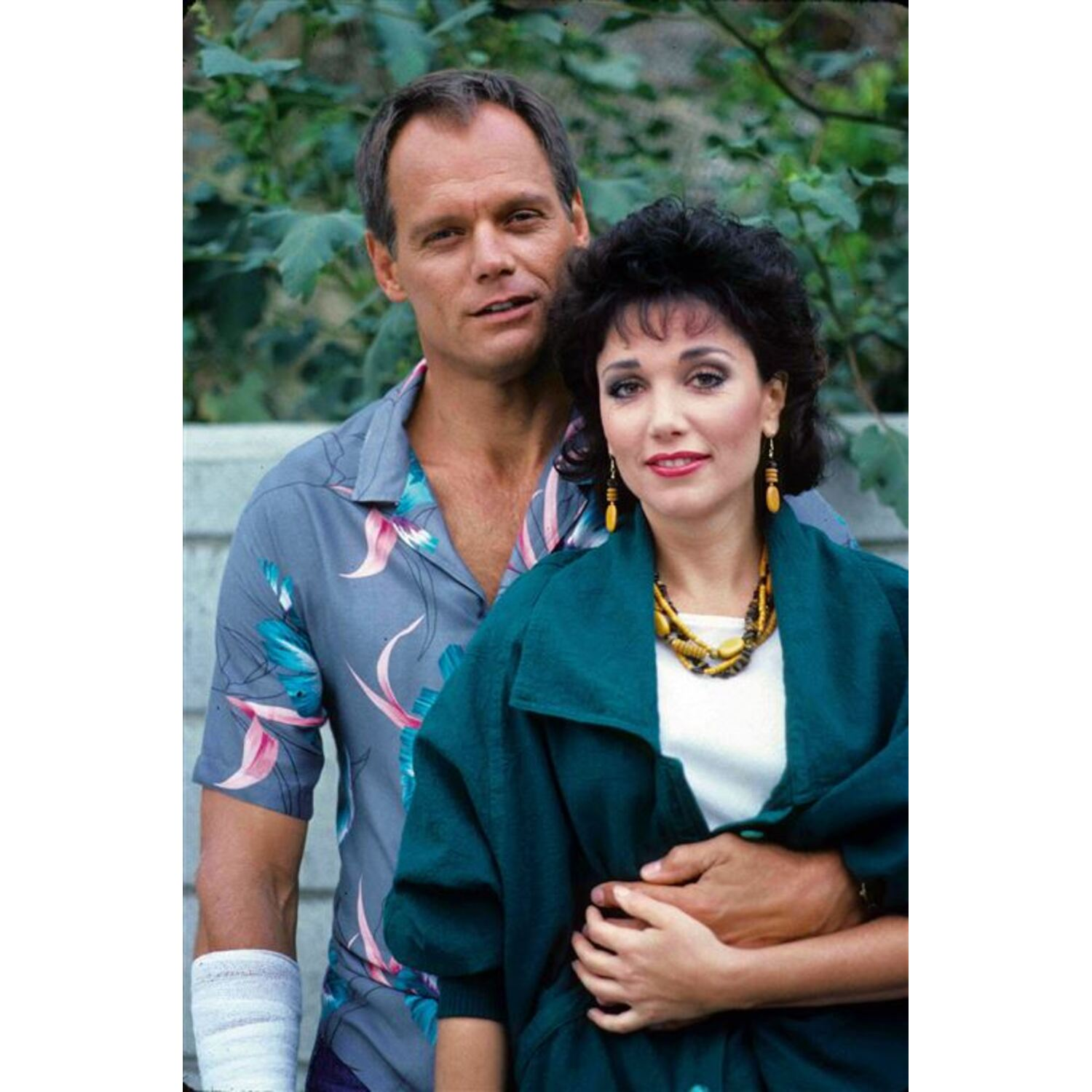 Een man en vrouw poseren, man heeft arm om vrouw, beiden kijken in de camera.