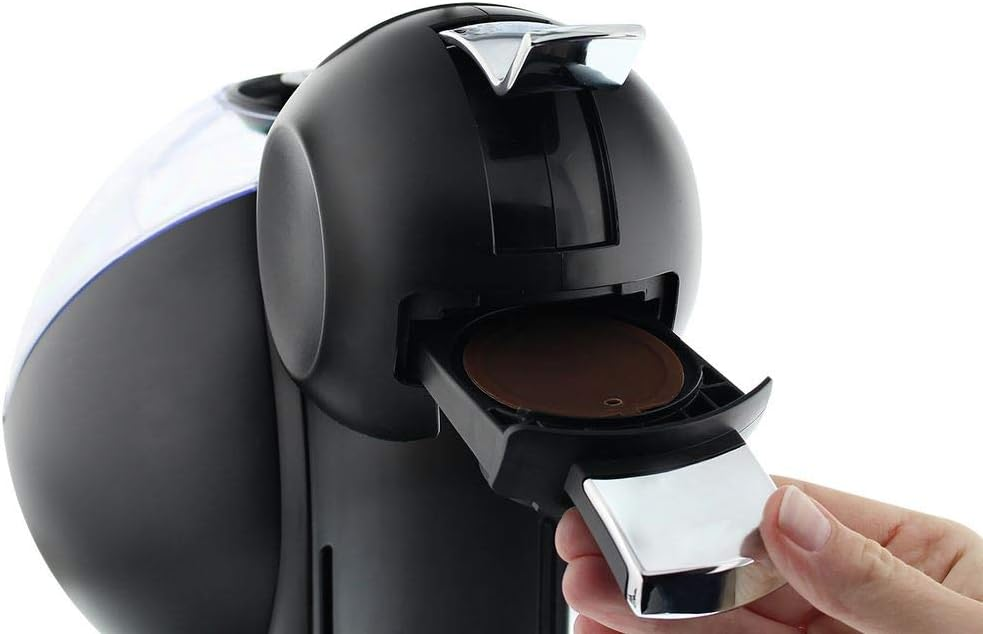 Un primer plano muestra una mano insertando una cápsula de café en una cafetera negra.