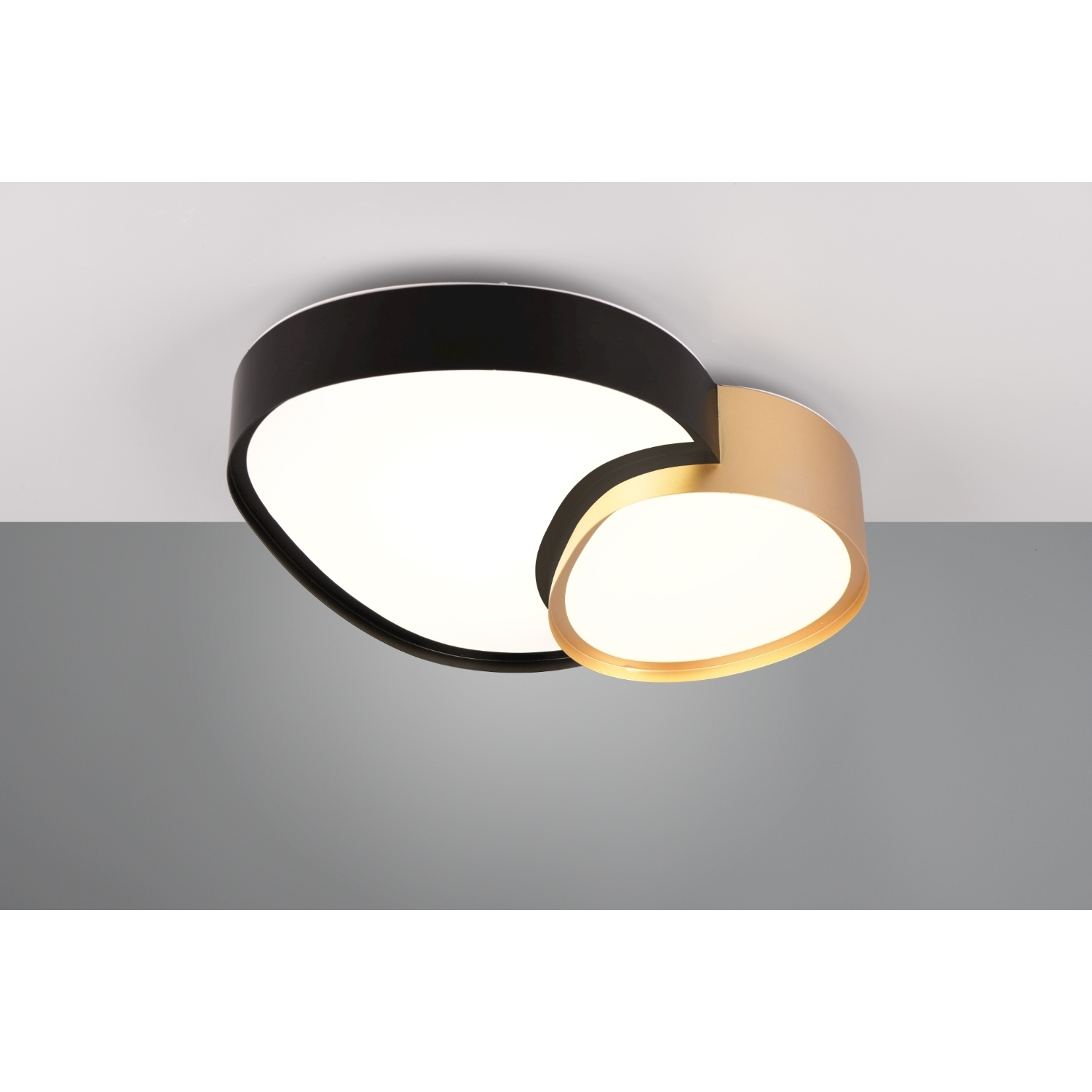 Un moderno apparecchio di illuminazione a soffitto. Ha elementi neri, bianchi e dorati. La luce è accesa.