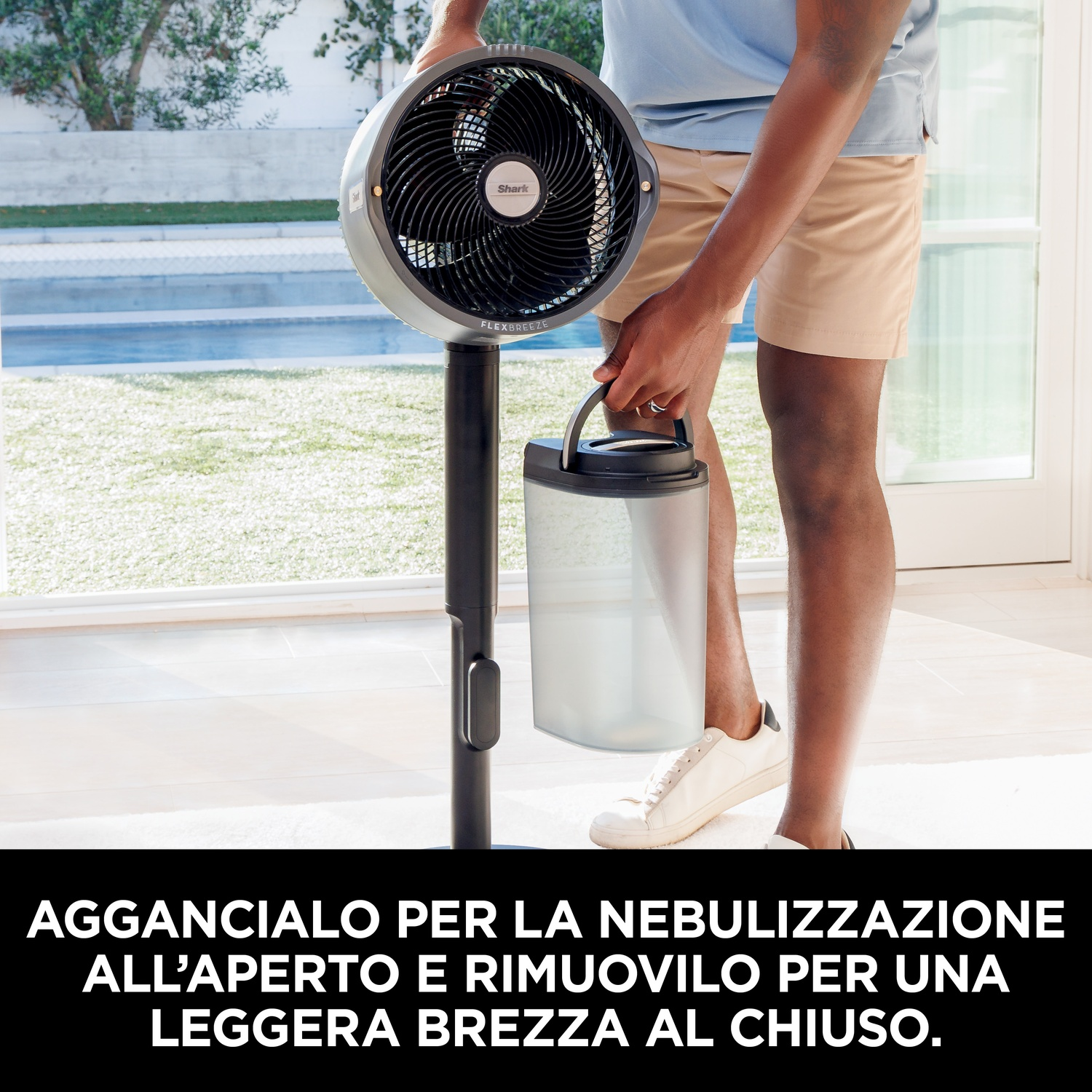 Uomo che tiene un ventilatore, vicino a una piscina. Il ventilatore ha un serbatoio d'acqua. Ventilatore nero e grigio.