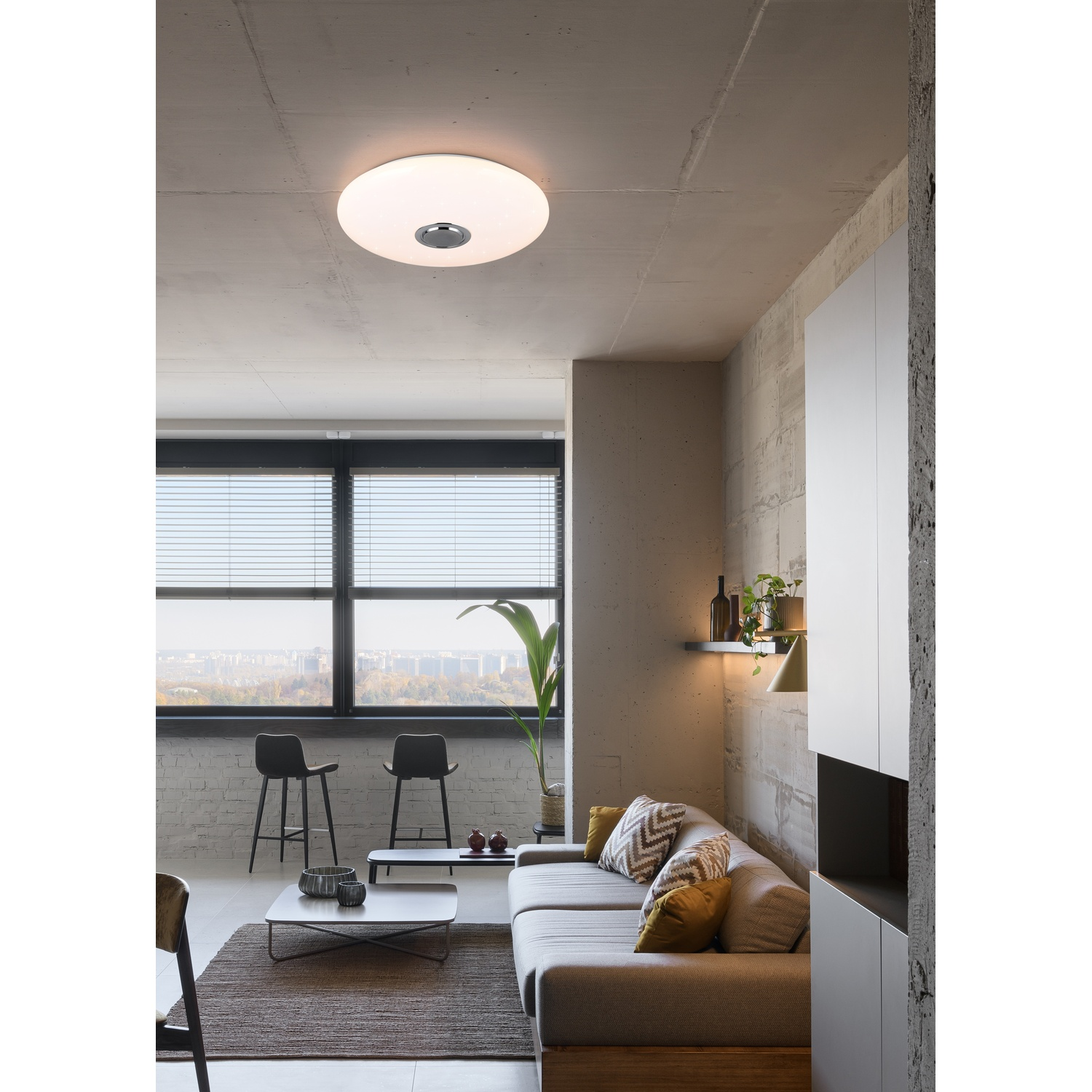 Soggiorno moderno con una grande lampada a soffitto, divano e parete in cemento.