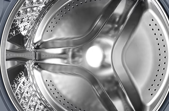 Błyszczące, nierdzewne wnętrze bębna pralki.