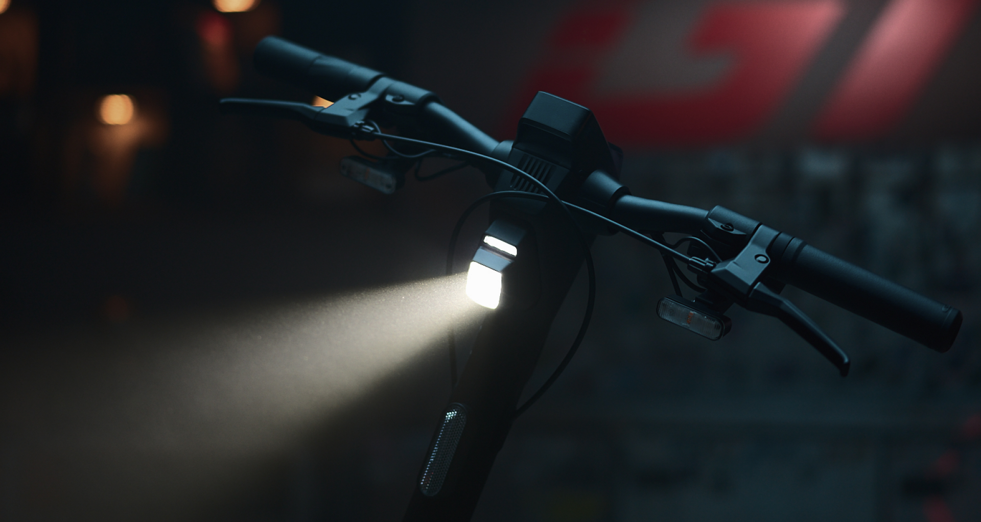Nahaufnahme des Lenkers eines E-Scooters mit hellem Scheinwerfer bei Nacht.