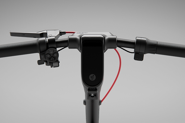 Gros plan du guidon de la trottinette. Noir avec boutons et câble rouge.