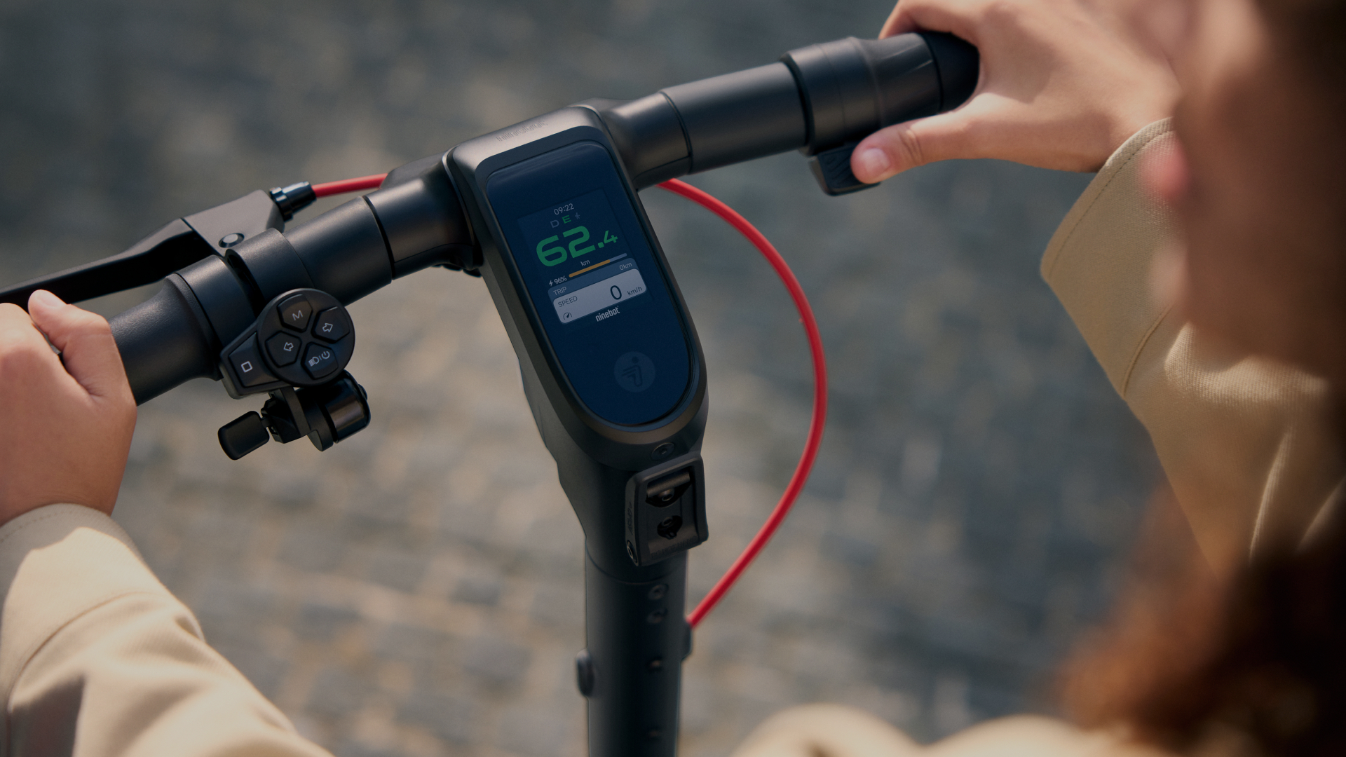 Mains sur le guidon d'un scooter. Le scooter a un affichage numérique indiquant la vitesse.
