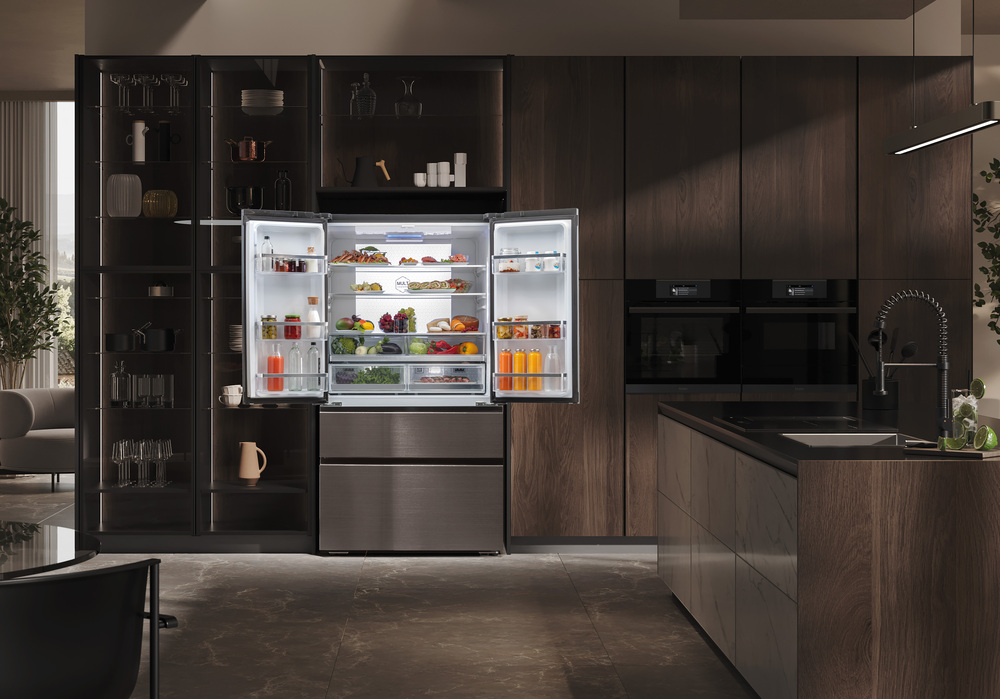 Cocina moderna con nevera abierta mostrando alimentos, armarios y cajones de madera oscura.