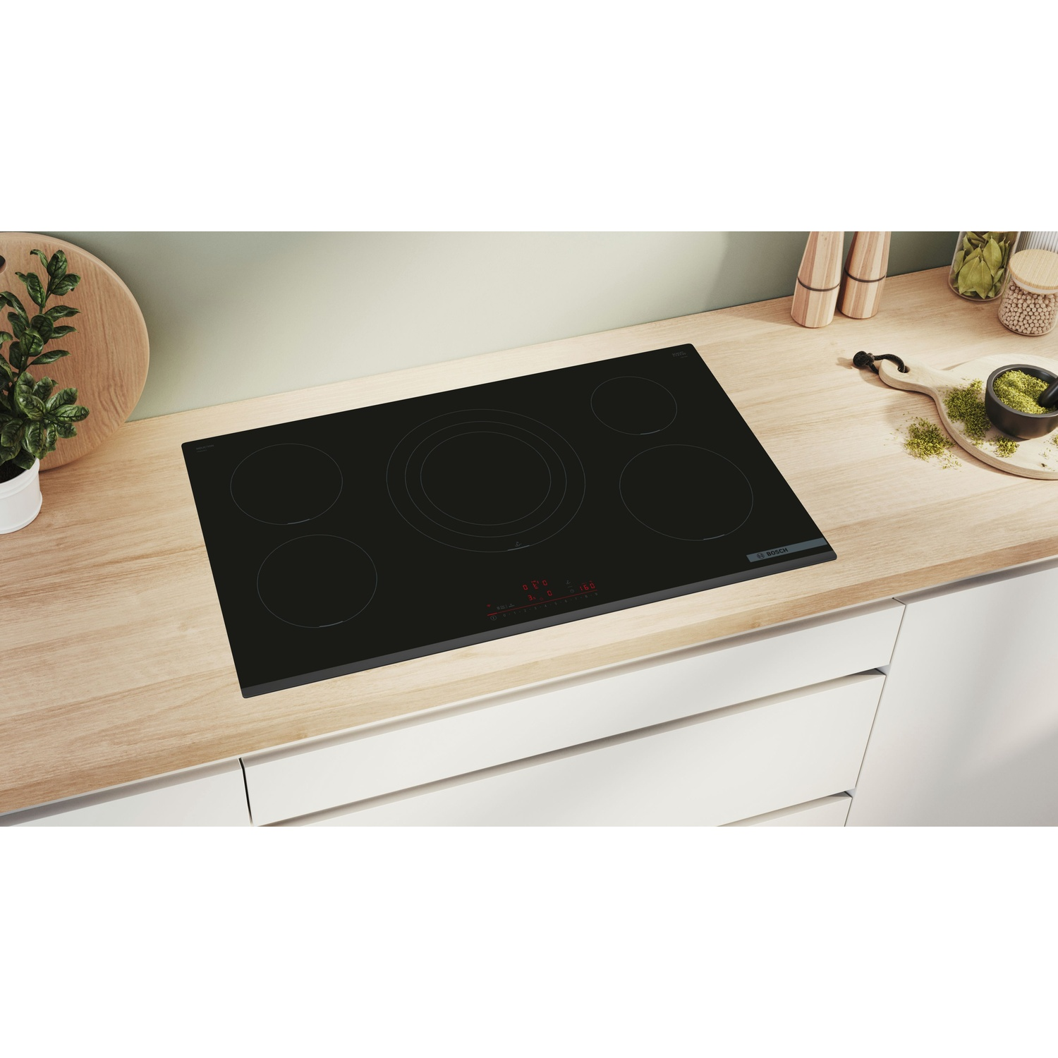 Piano cottura nero con cinque fuochi. È posto su un piano di lavoro in legno chiaro.