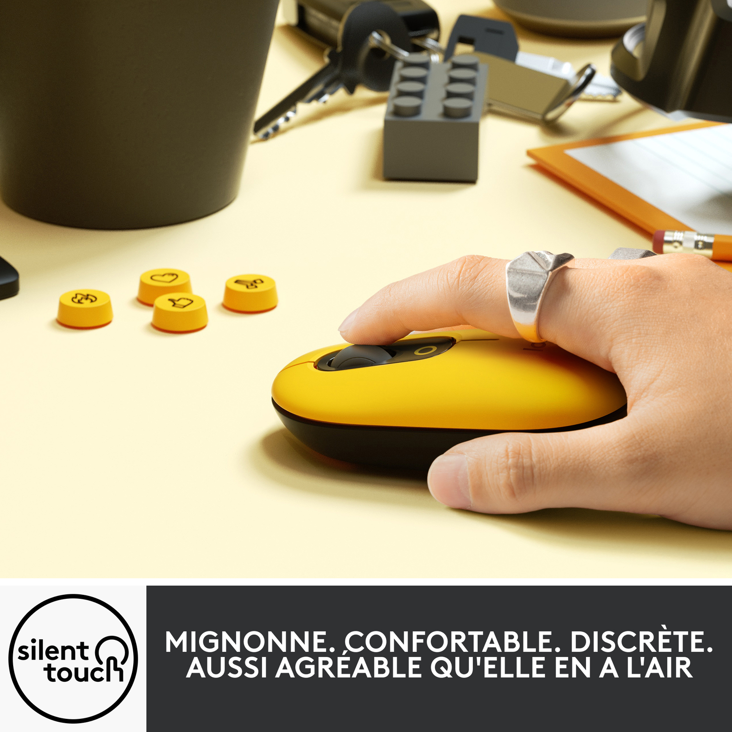 Main utilisant une souris sans fil jaune sur une surface jaune.