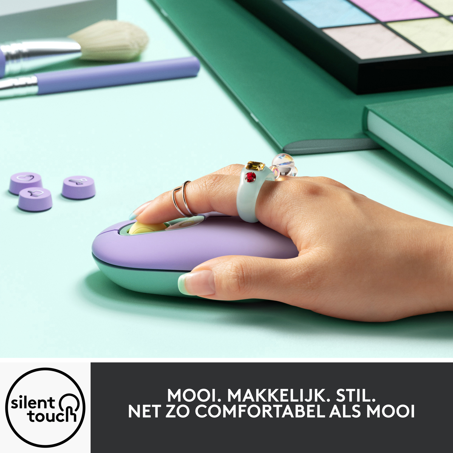 Een hand op een paarse en mintkleurige muis. Ringen en accessoires op de hand.