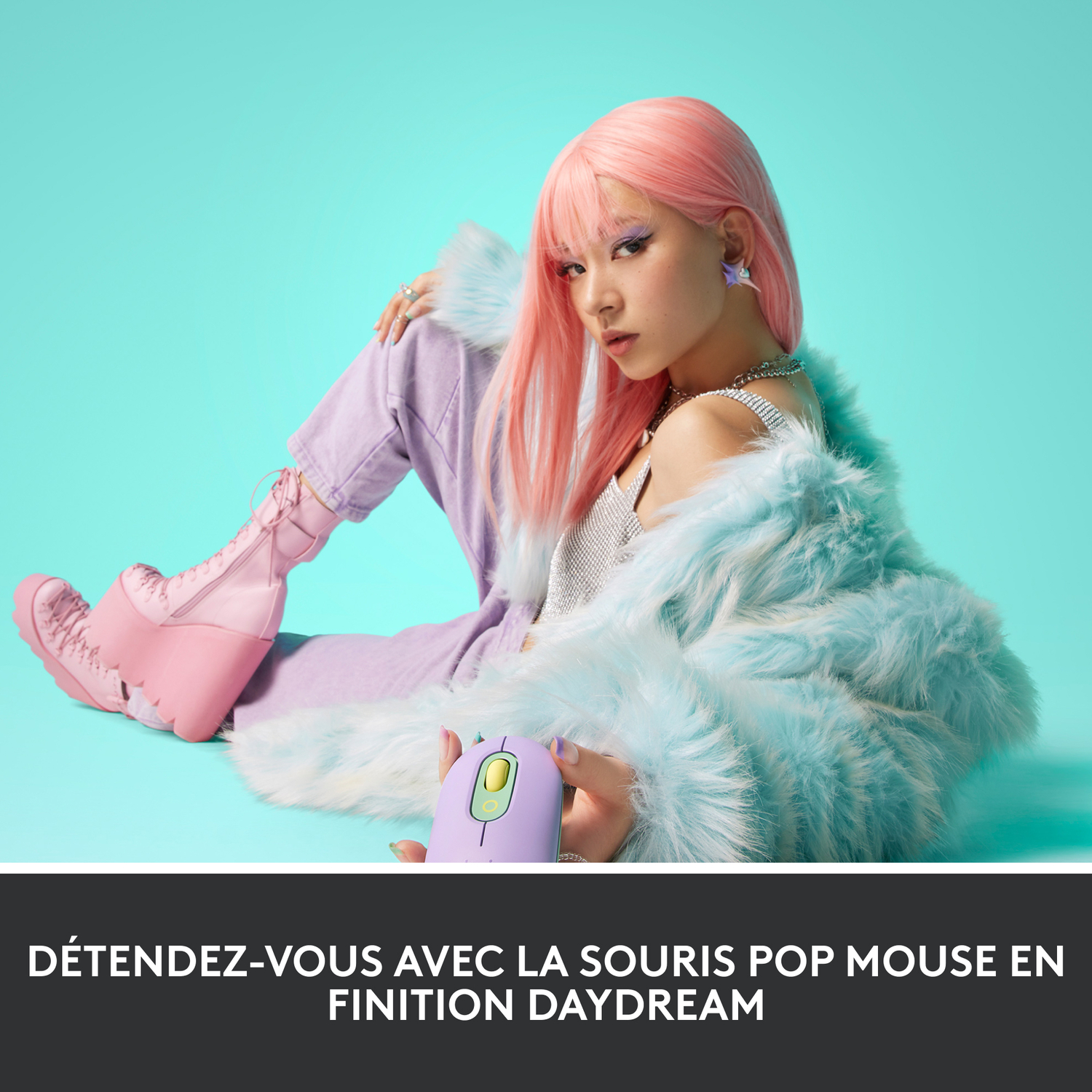 Femme aux cheveux roses, souris violette, assise sur surface bleue.