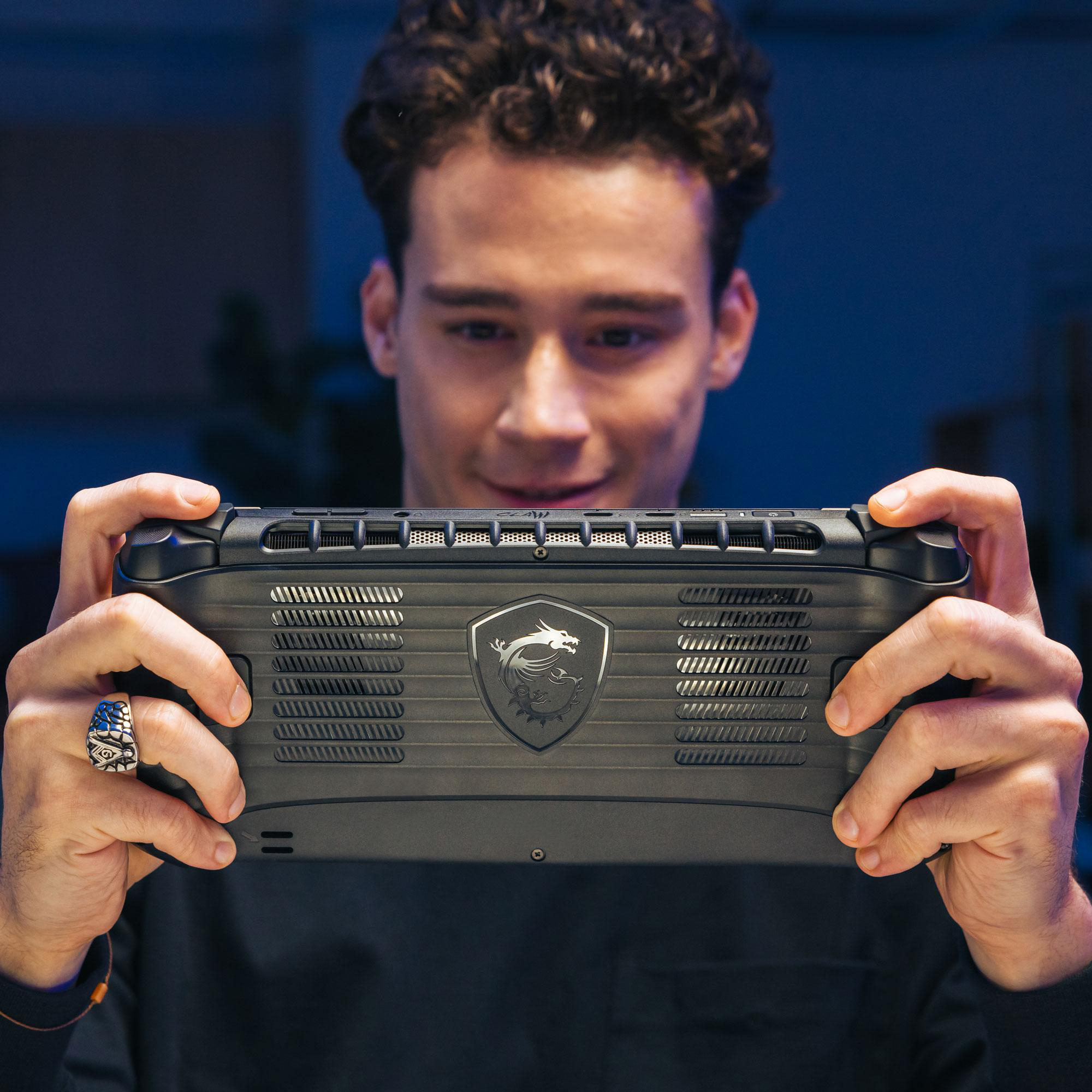 Eine Person hält ein schwarzes Handheld-Gaming-Gerät. Er lächelt in die Kamera.