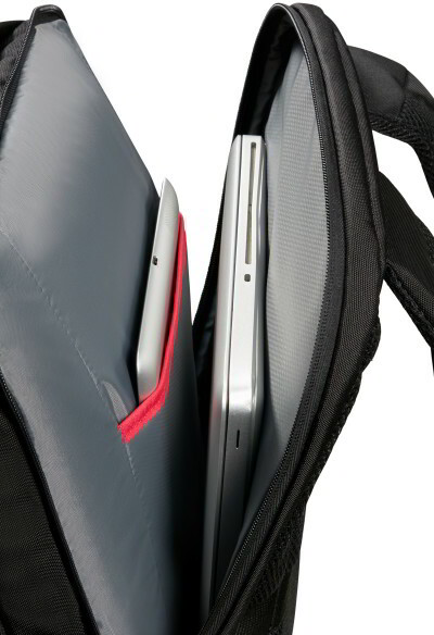 Egy hátizsák belsejében egy tablet és egy laptop látható külön rekeszekben, szürke háttér előtt.
