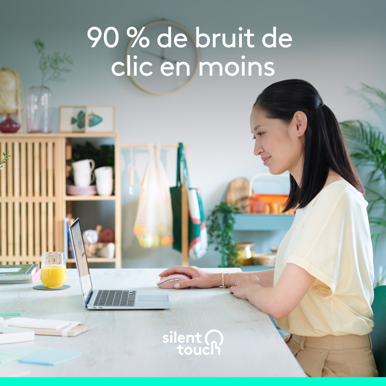 Une femme assise à une table travaillant sur un ordinateur portable. Un verre de jus est sur la table.