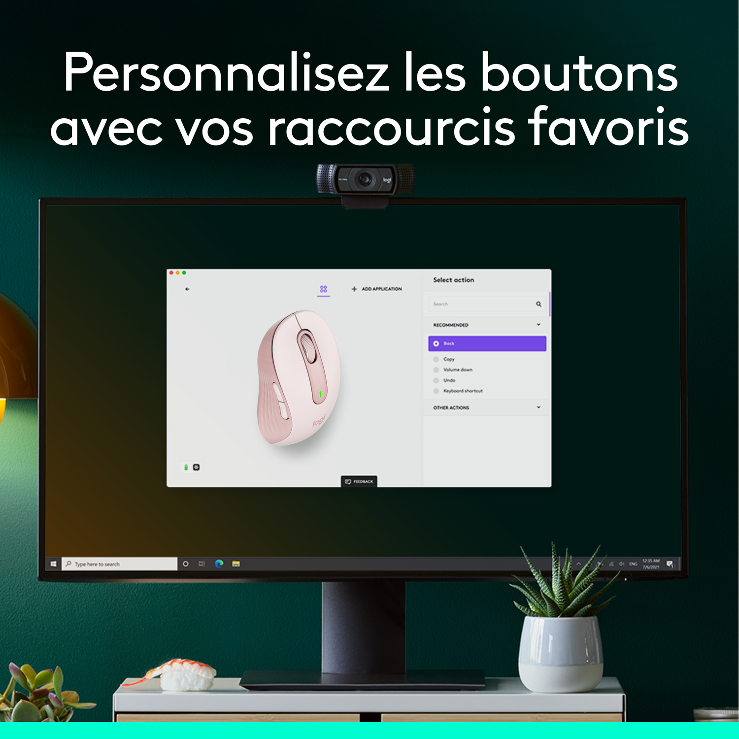 Un moniteur d'ordinateur avec une souris et une webcam. Un mur vert est en arrière-plan.