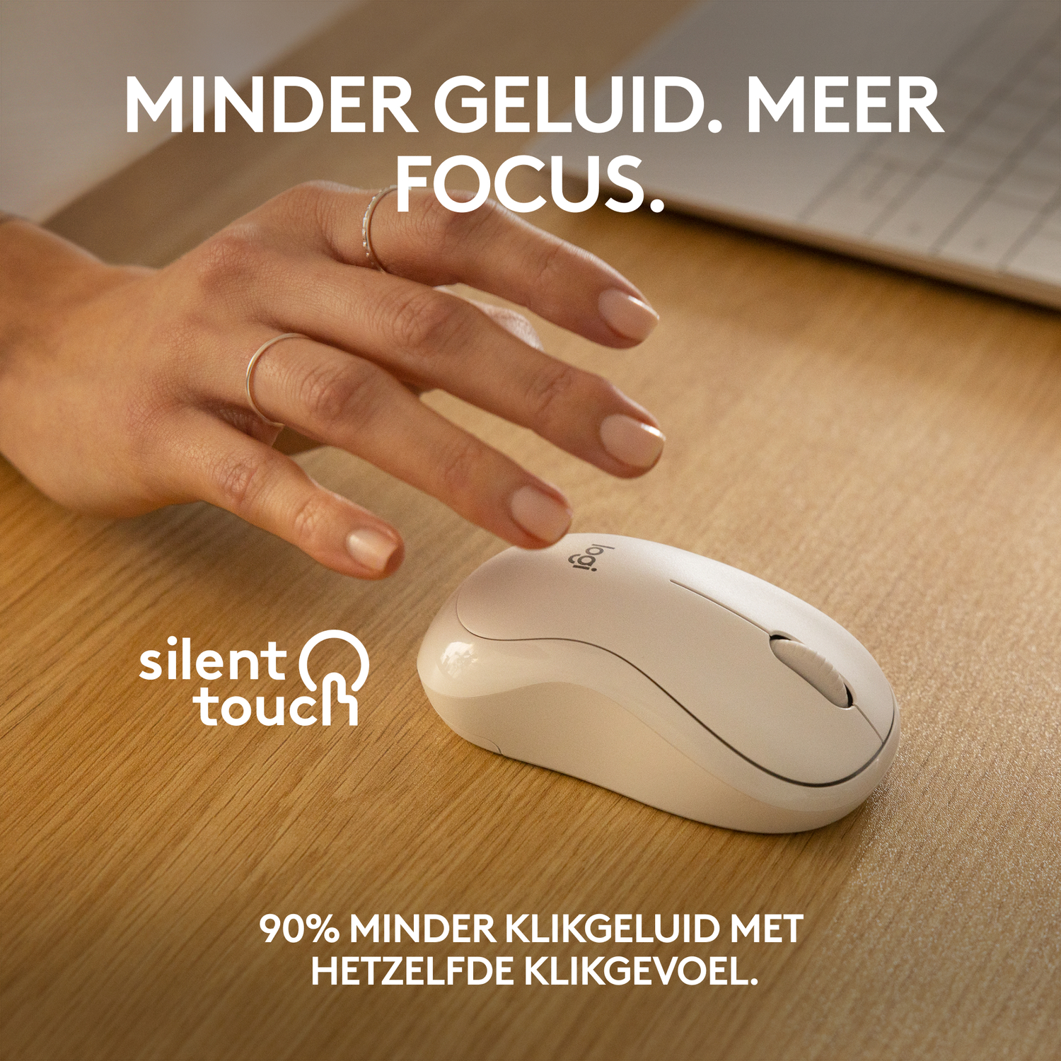 A white computer mouse on a wooden surface. The mouse is near a hand.