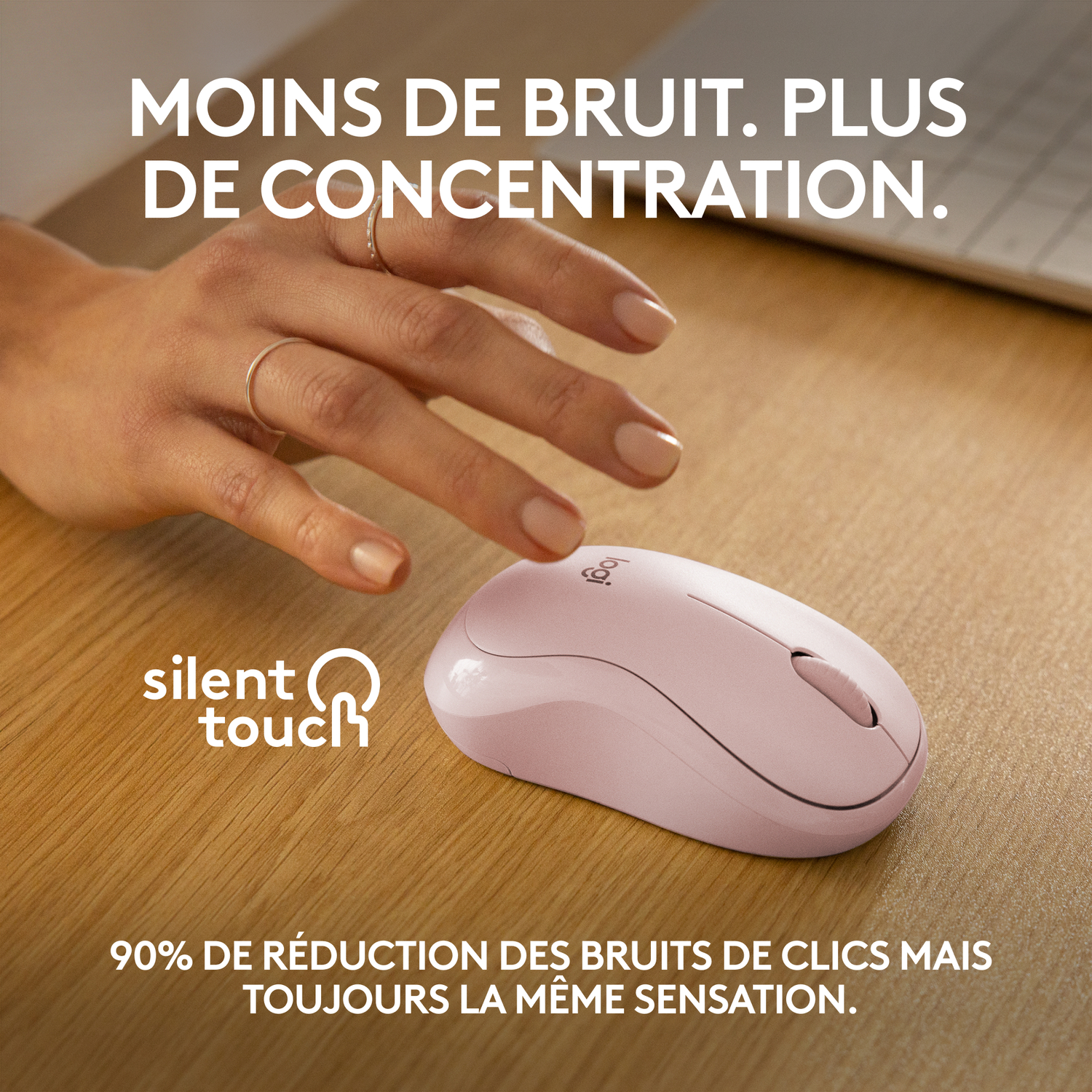 Une souris sans fil rose sur un bureau en bois, avec du texte sur les clics silencieux.