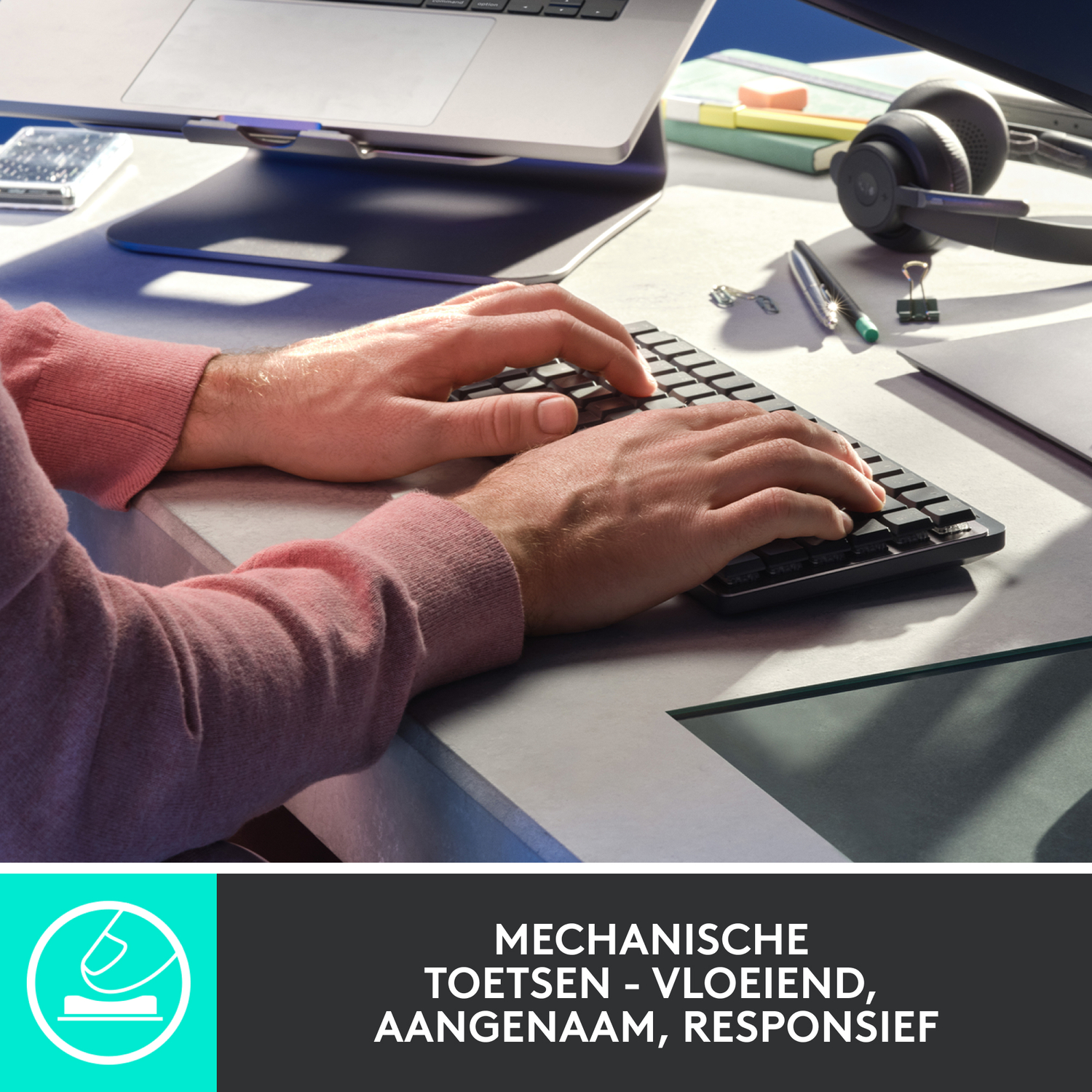 Handen die typen op een zwart toetsenbord. Roze shirt, bureau en andere items.