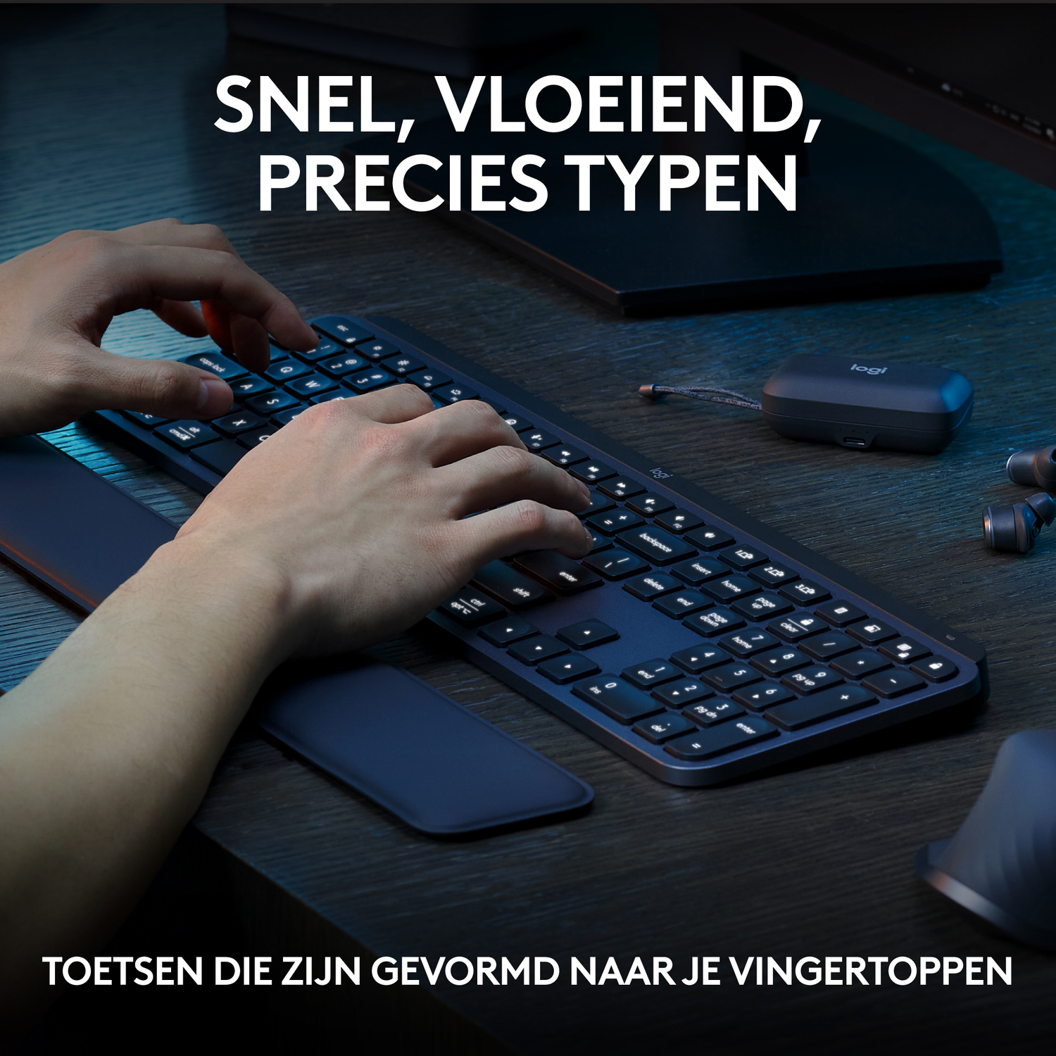 Hands typing on a dark keyboard with a wrist rest. The keyboard is on a wooden desk.