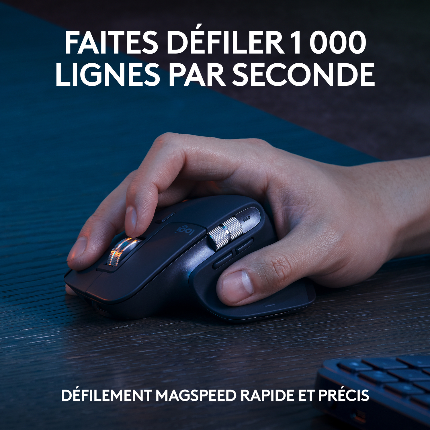 La main d'une personne est sur une souris noire, sur une surface en bois.