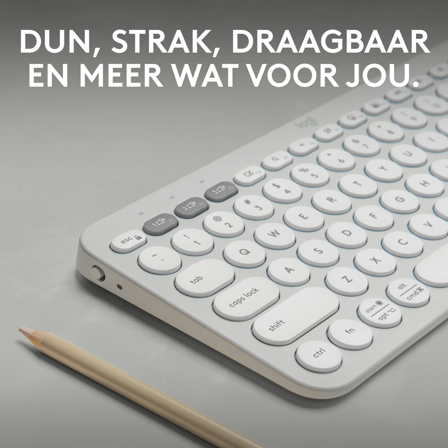 A gray keyboard with white keys on a light gray surface, with a pencil.