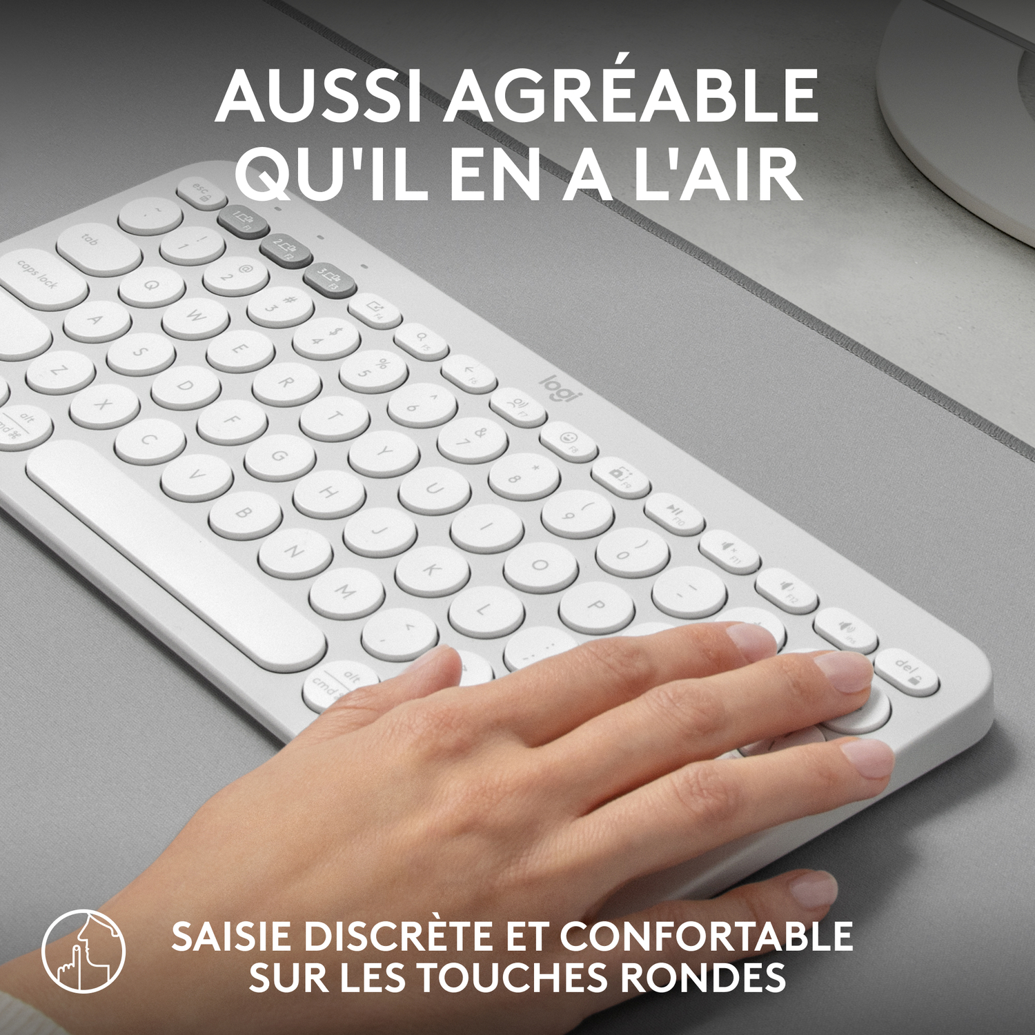 Clavier blanc, avec une main dessus. Le clavier a des touches rondes et un design minimaliste.