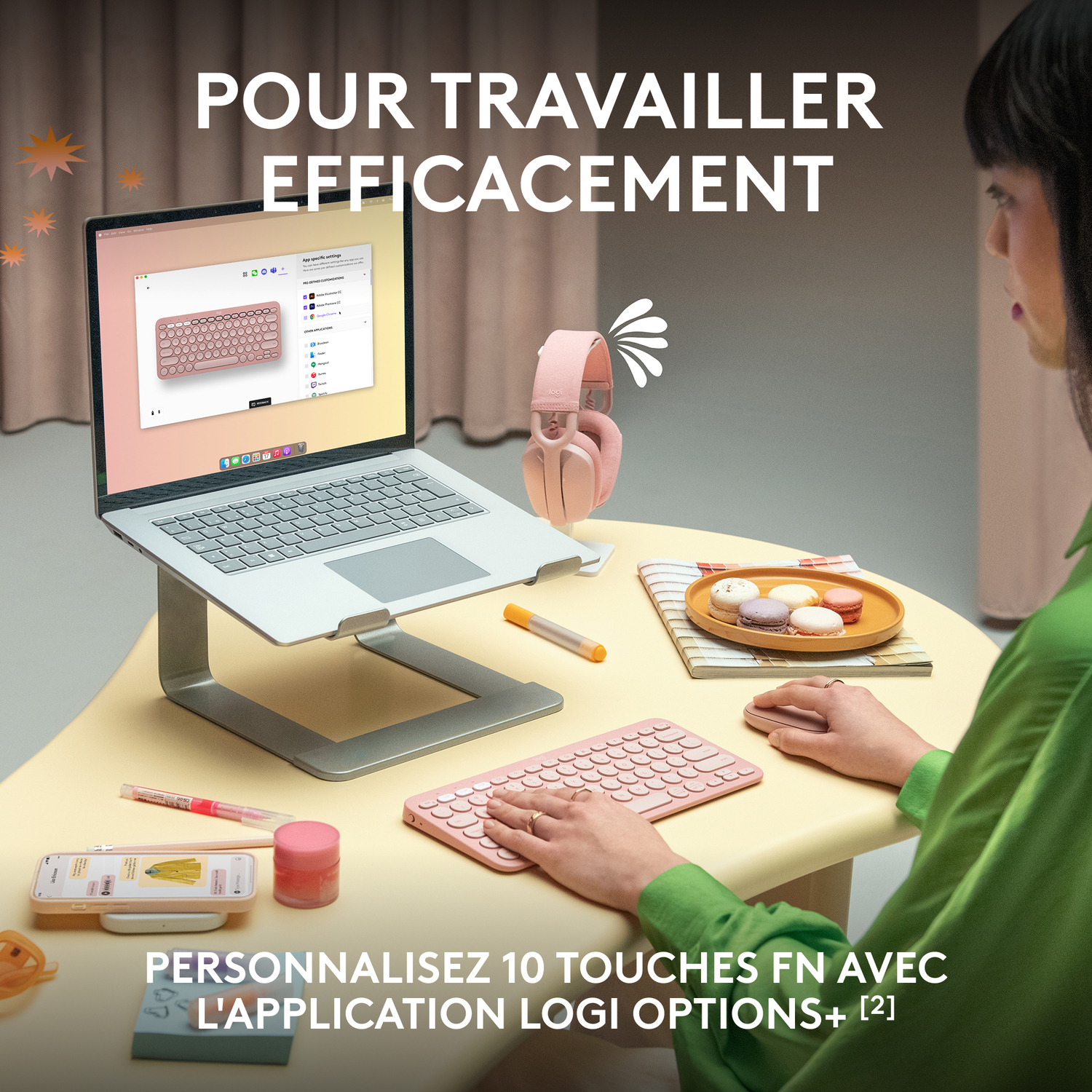 Femme travaille sur un ordinateur portable avec clavier rose, casque et accessoires sur table jaune.