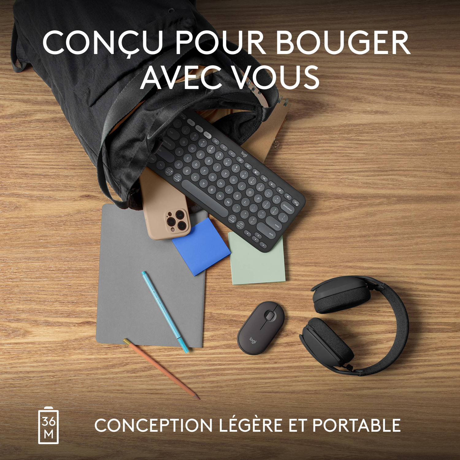 Scène de bureau : clavier, casque, souris, téléphone, bloc-notes, stylo et sac noirs.