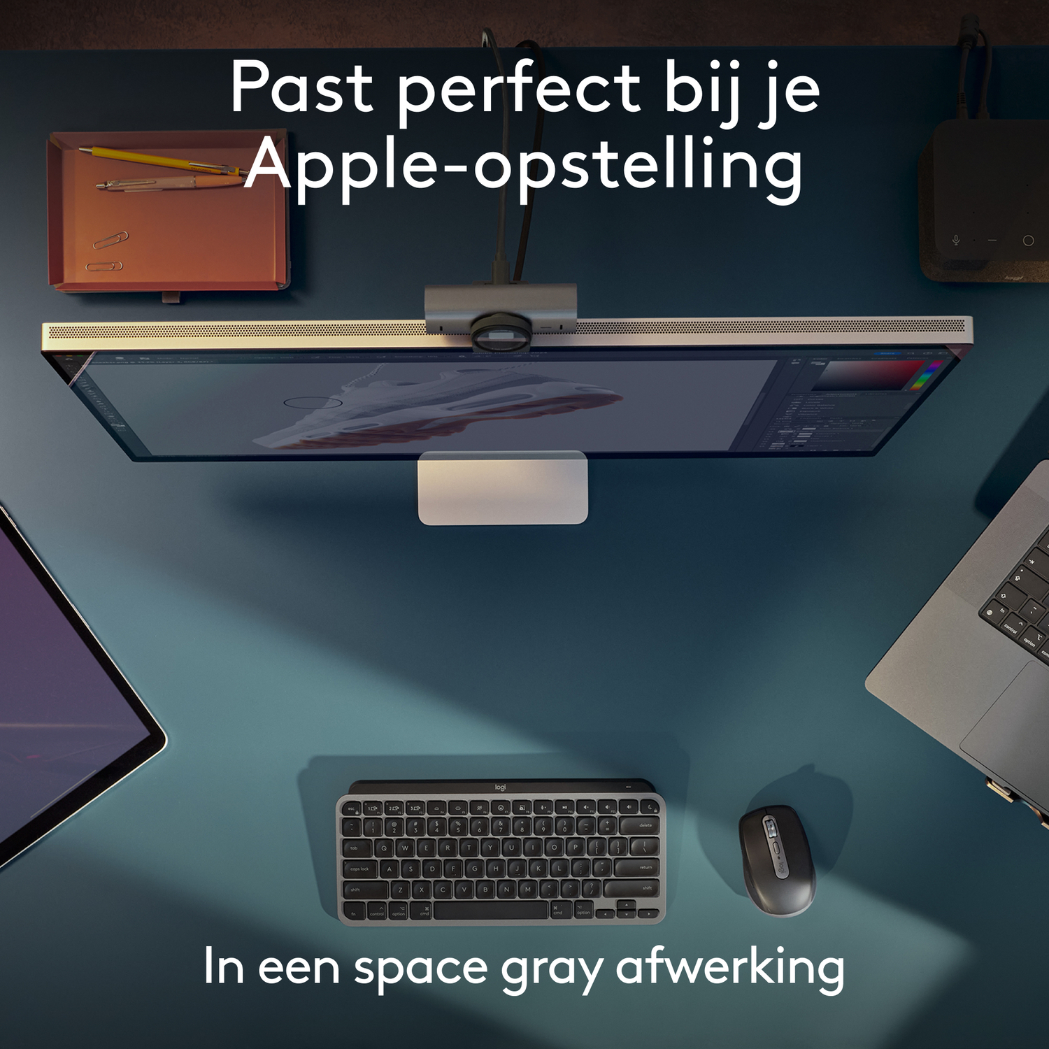 Werkruimte met monitor, toetsenbord, muis en accessoires op een turquoise bureau.