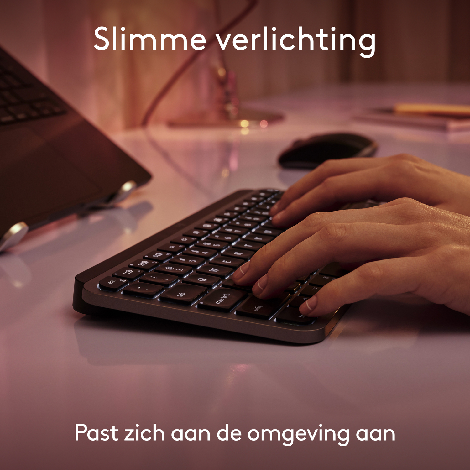 Handen typen op verlicht toetsenbord. Het toetsenbord staat op een bureau, lichten reflecteren.