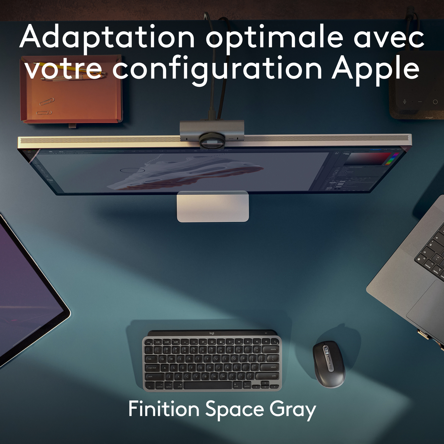 Vue aérienne d'un bureau avec écran Apple, clavier, souris et autres appareils technologiques.