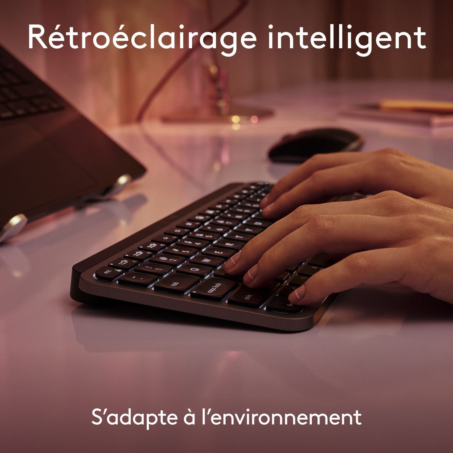 Mains tapant sur un clavier noir rétroéclairé. Le texte dit rétroéclairage intelligent s'adapte à l'environnement.
