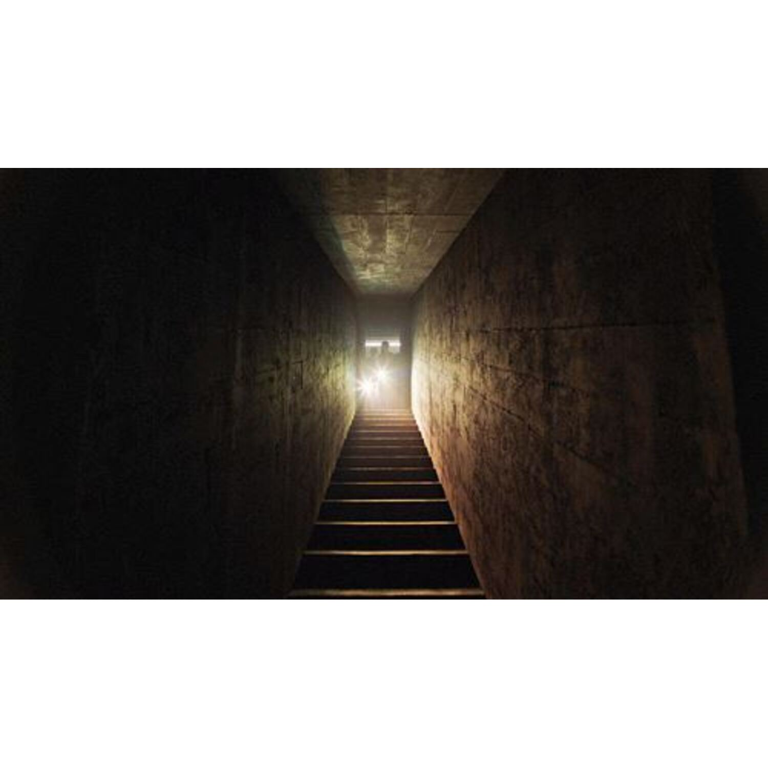 A dark hallway with stairs leading up. Two figures are at the top, with light shining.