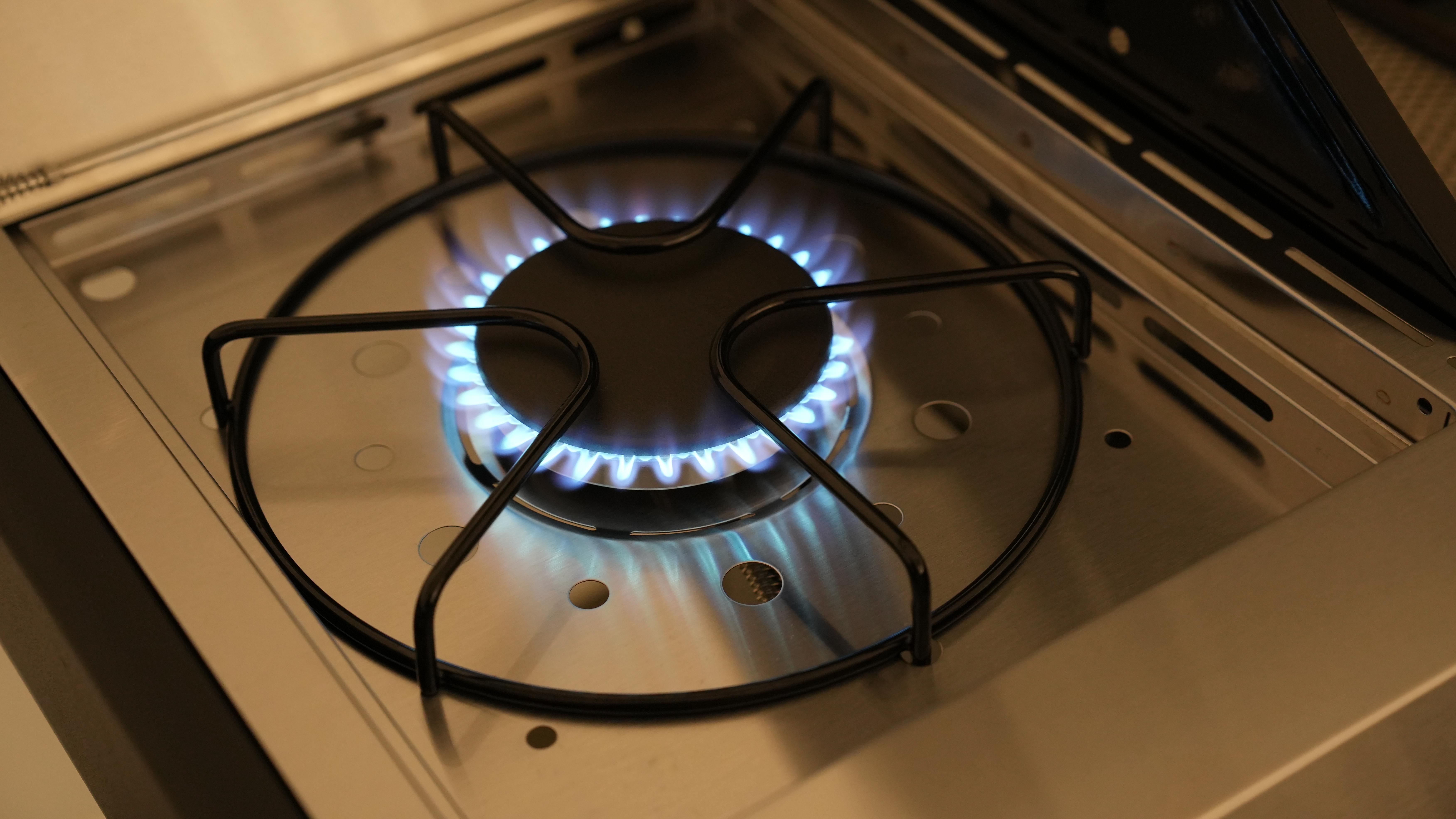 Blaue Flamme brennt auf einem Metallherd. Kreisförmiger Brennerring. Nahaufnahme.