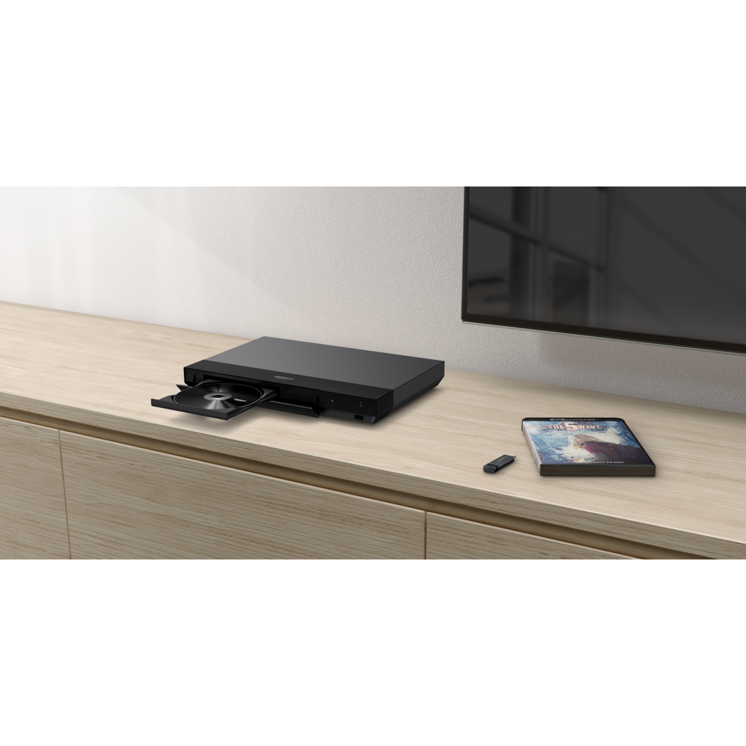 A black DVD player with a disc and a remote on a table.