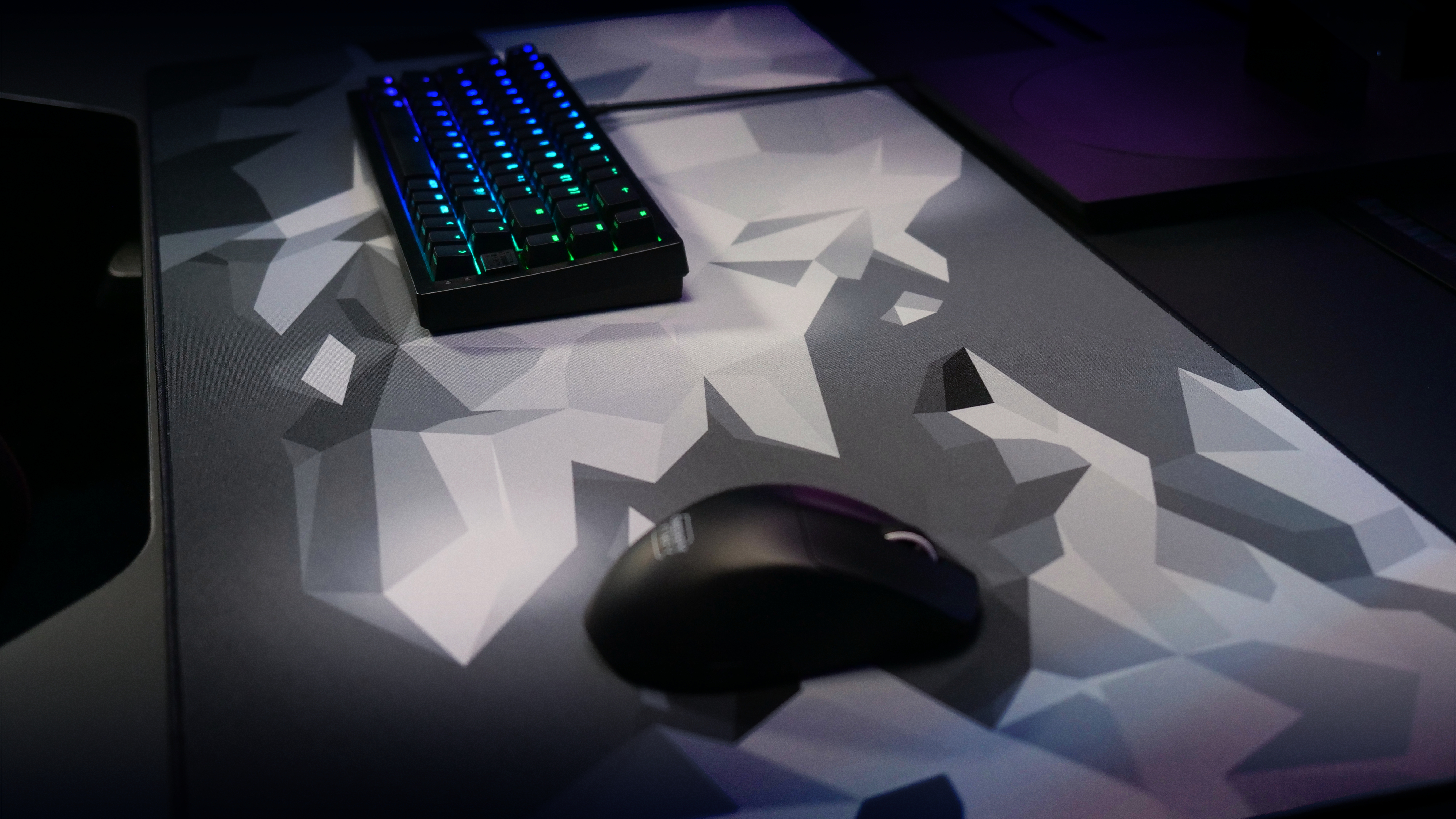 Tastatur mit regenbogenfarbenen Tasten auf geometrischer Matte, Maus.