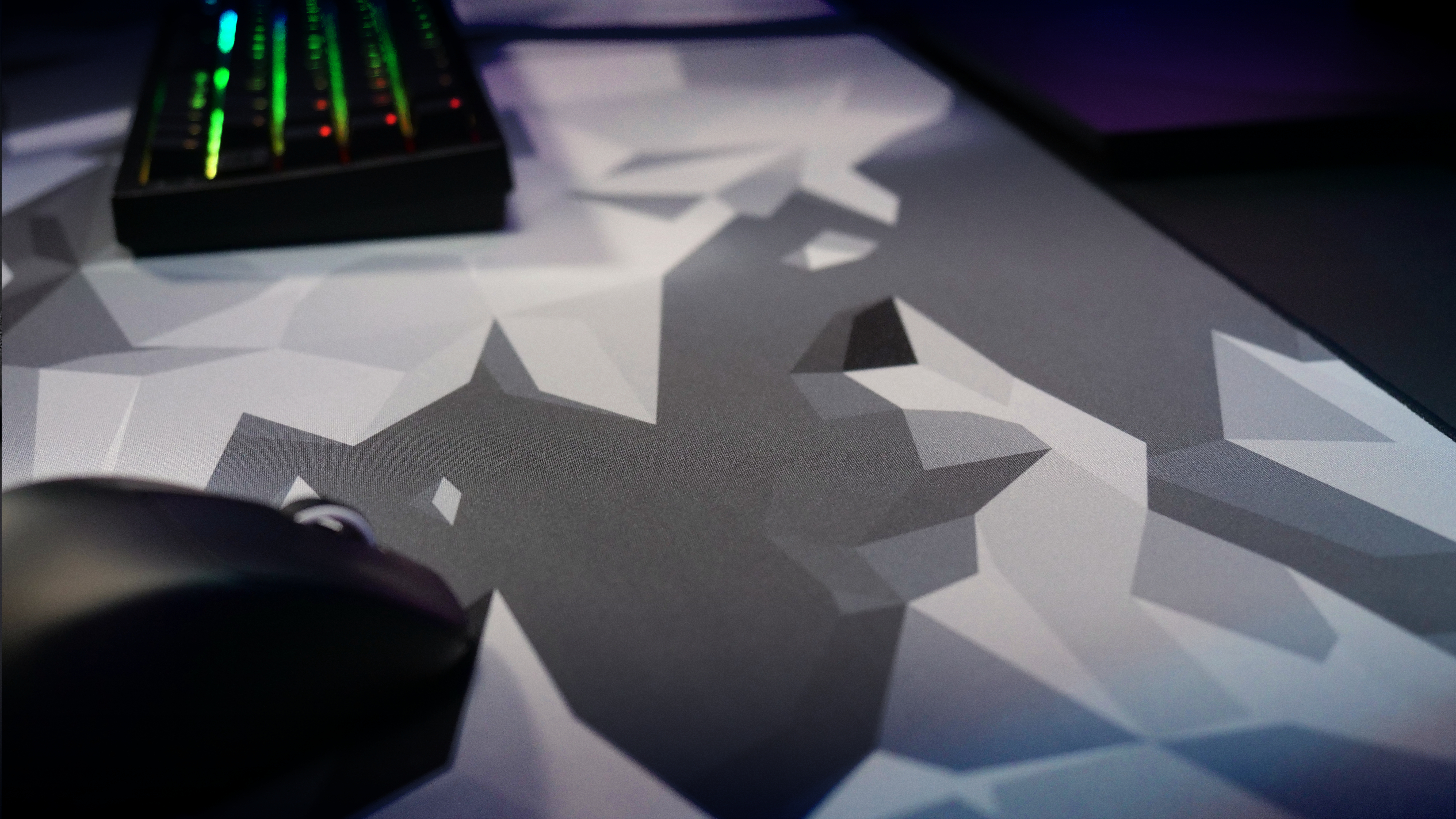 Gaming-Maus und -Tastatur auf einem geometrisch gemusterten Mauspad. Dunkler Hintergrund.
