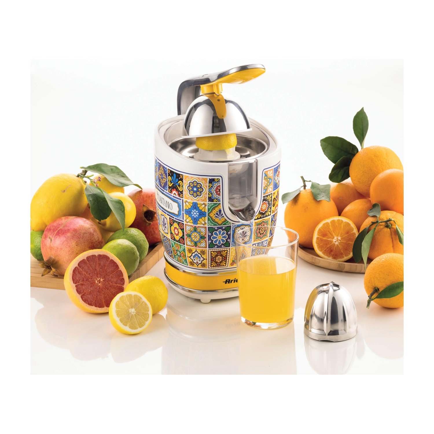 Uno spremiagrumi con limoni e arance, con un bicchiere di succo.